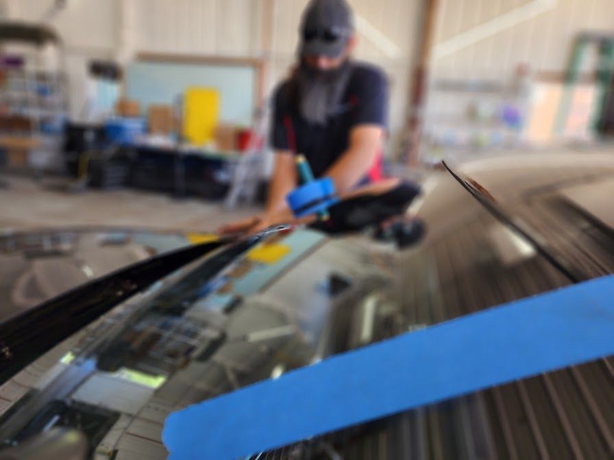 A man is fixing a windshield on a car in a garage.