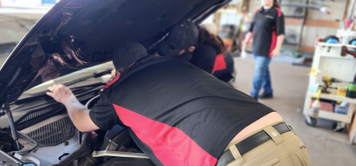 A man is looking under the hood of a car.