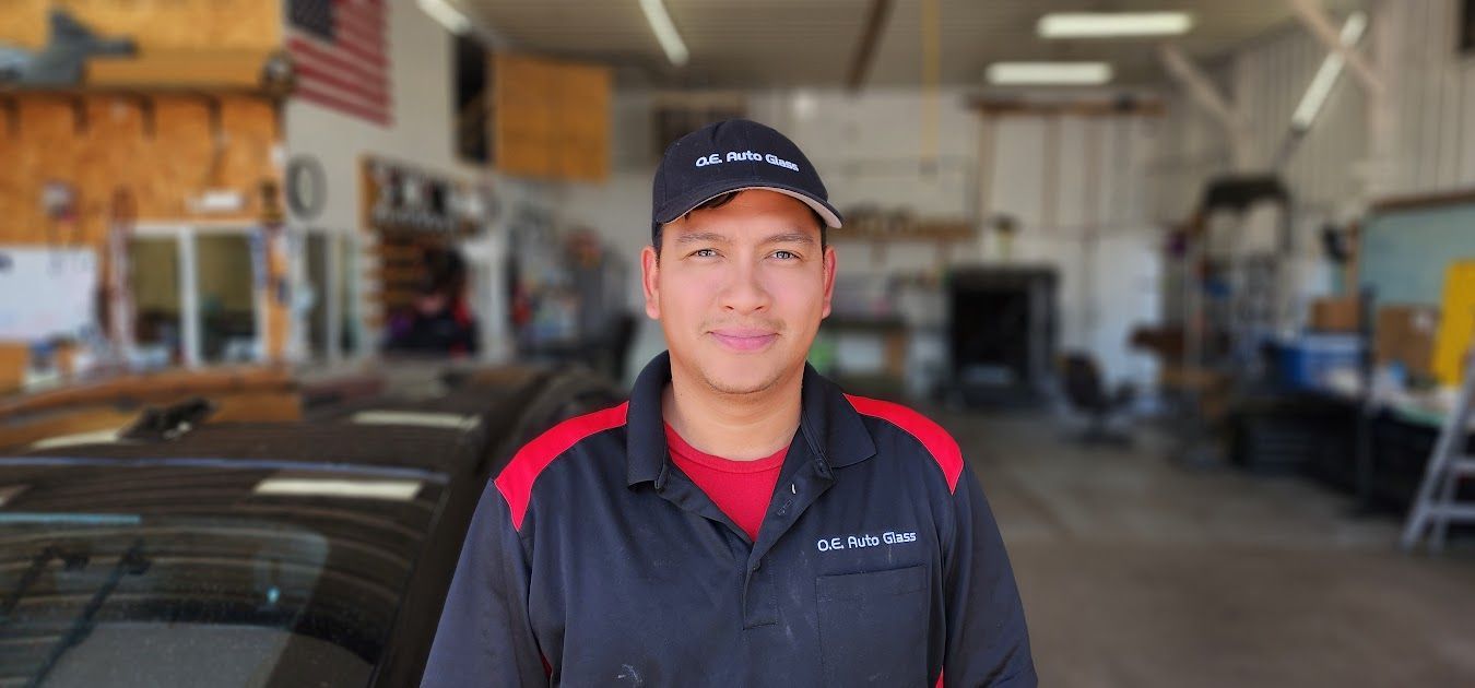 A man is standing in front of a car in a garage.