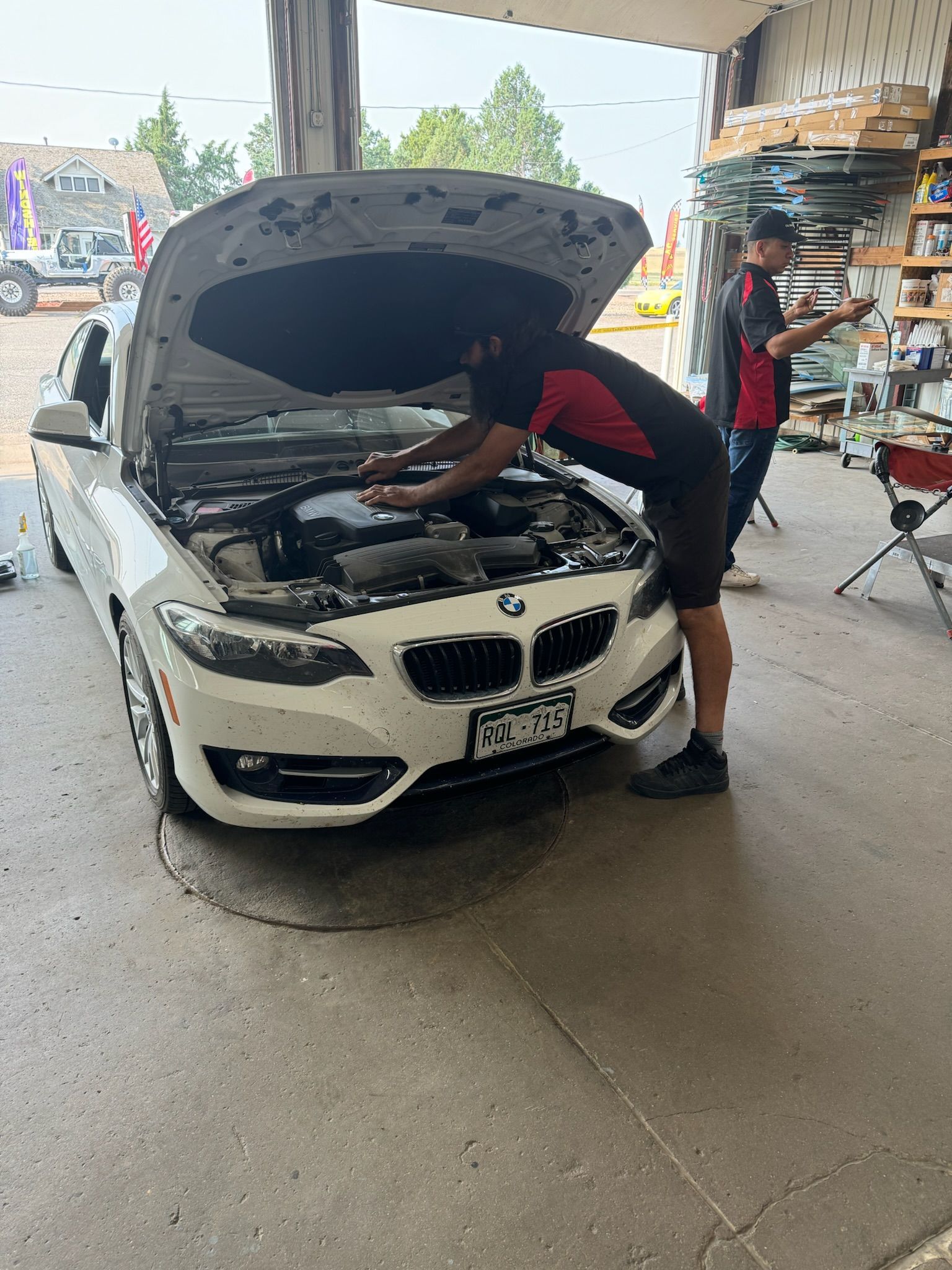A man is working on the engine of a white bmw in a garage.