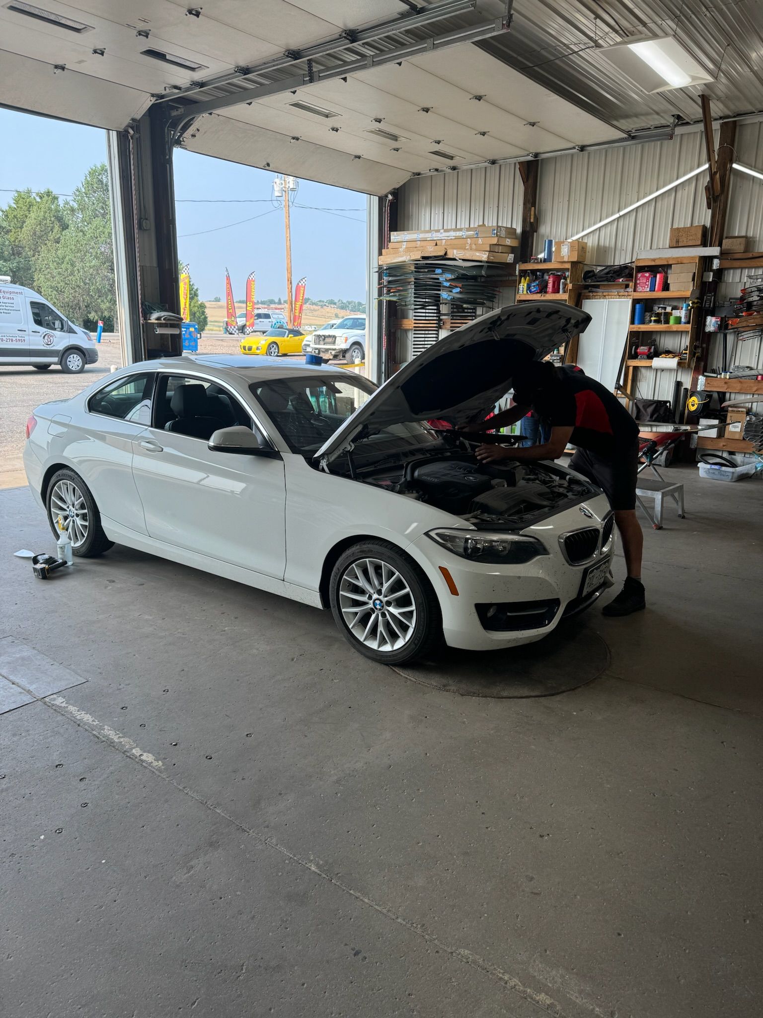 A man is working on a white car in a garage.