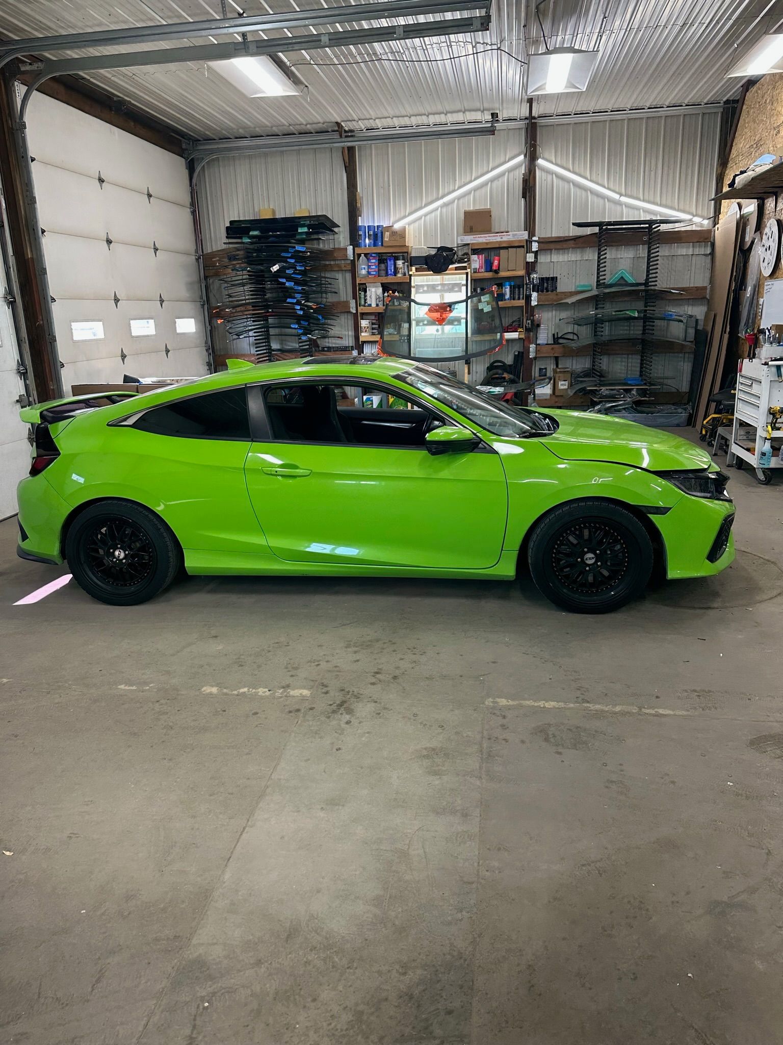 A green car is parked in a garage.