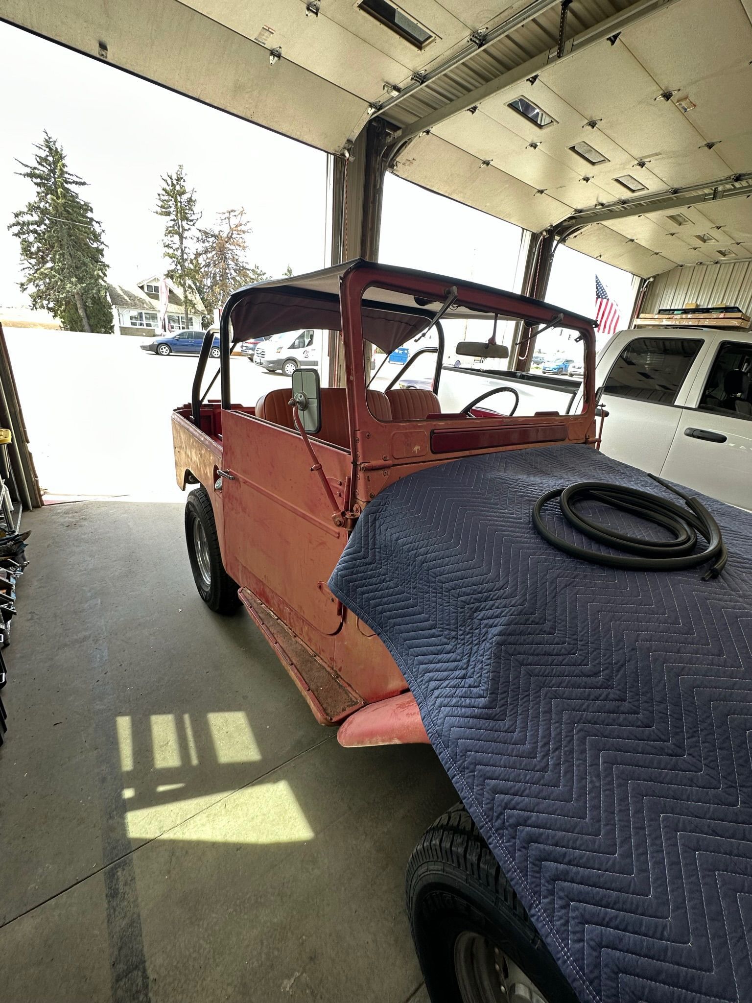 A red jeep is parked in a garage under a garage door.