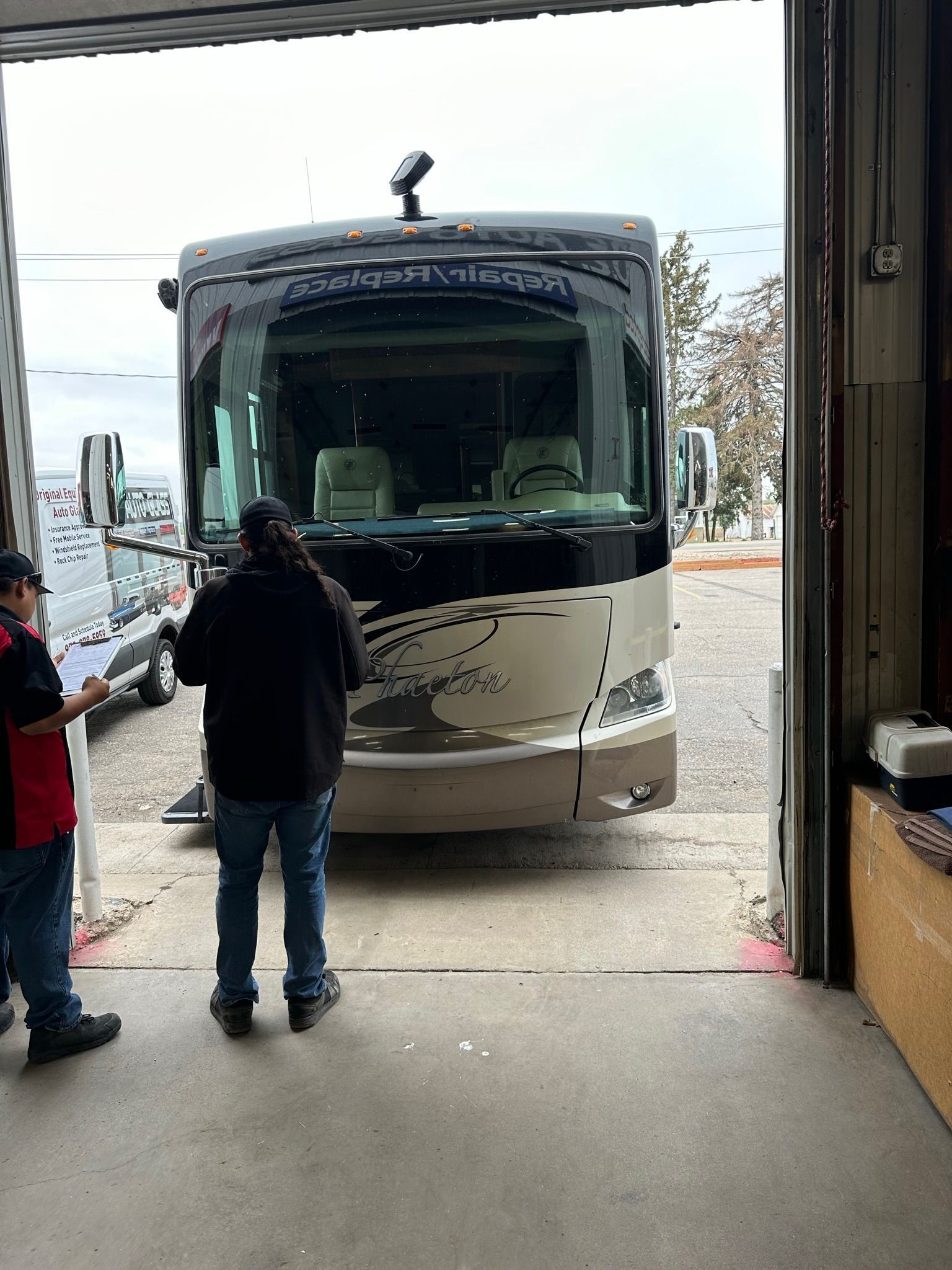 A man is standing in front of a rv in a garage.