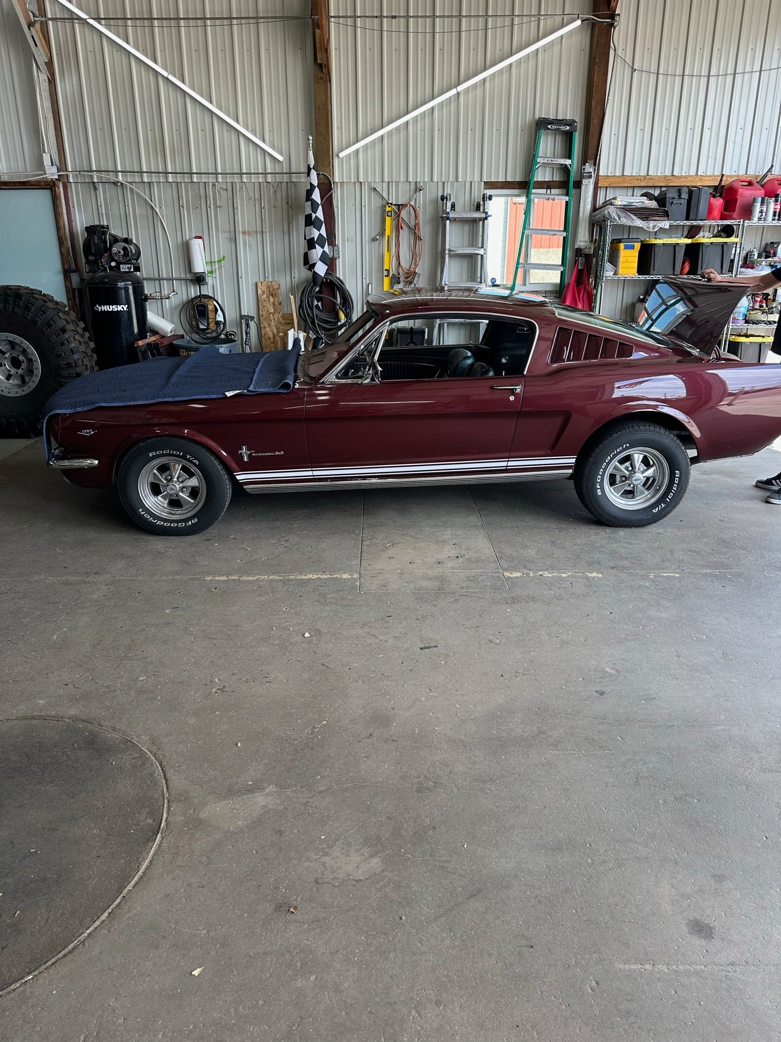 A red mustang convertible is parked in a garage.