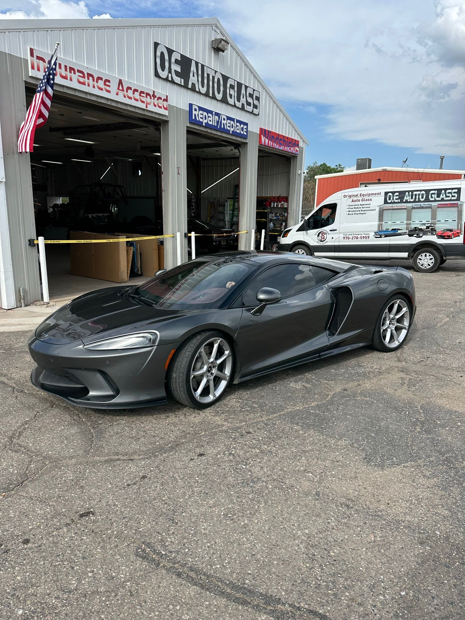 A gray sports car is parked in front of a garage.