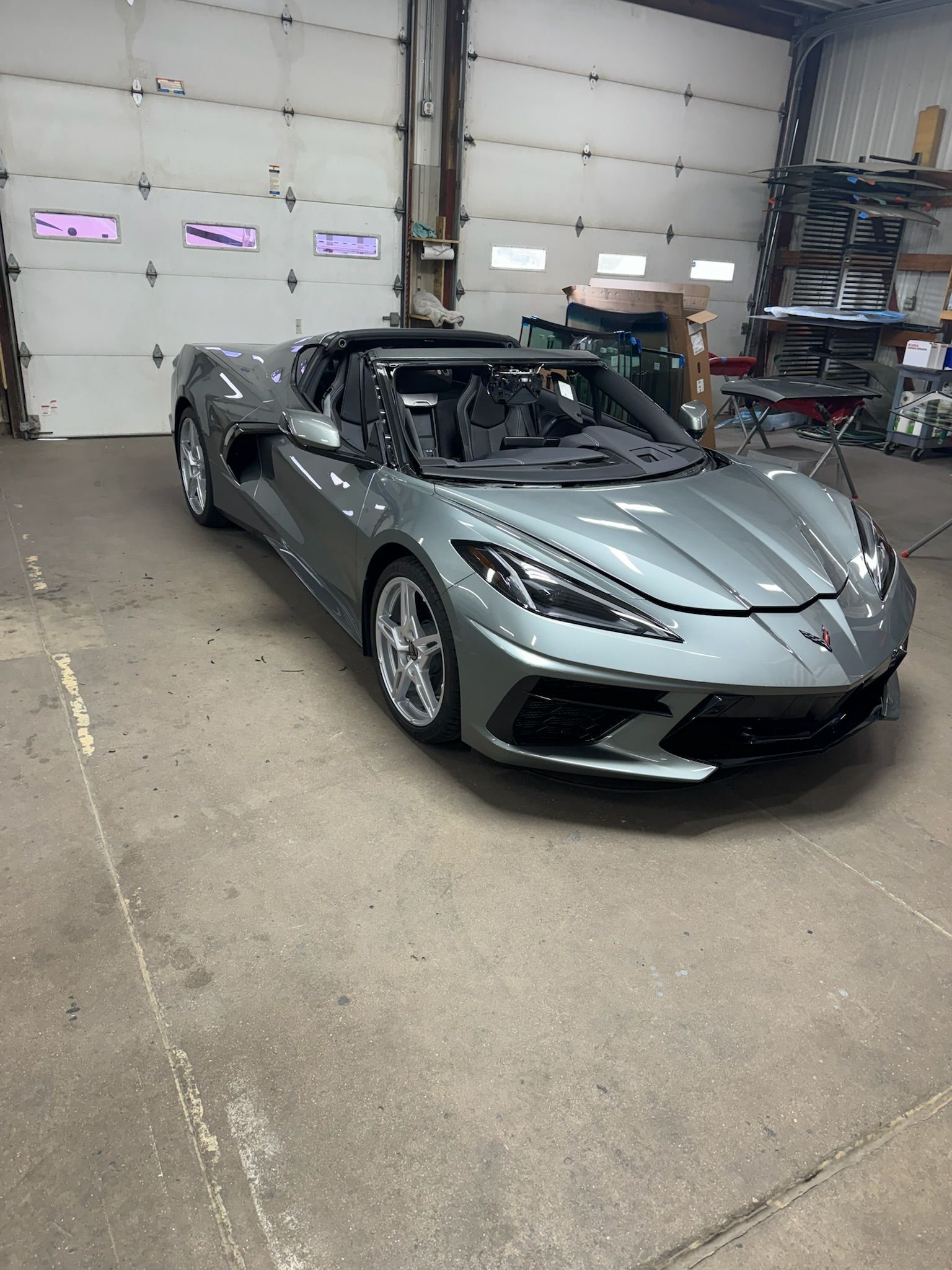 A gray corvette convertible is parked in a garage.