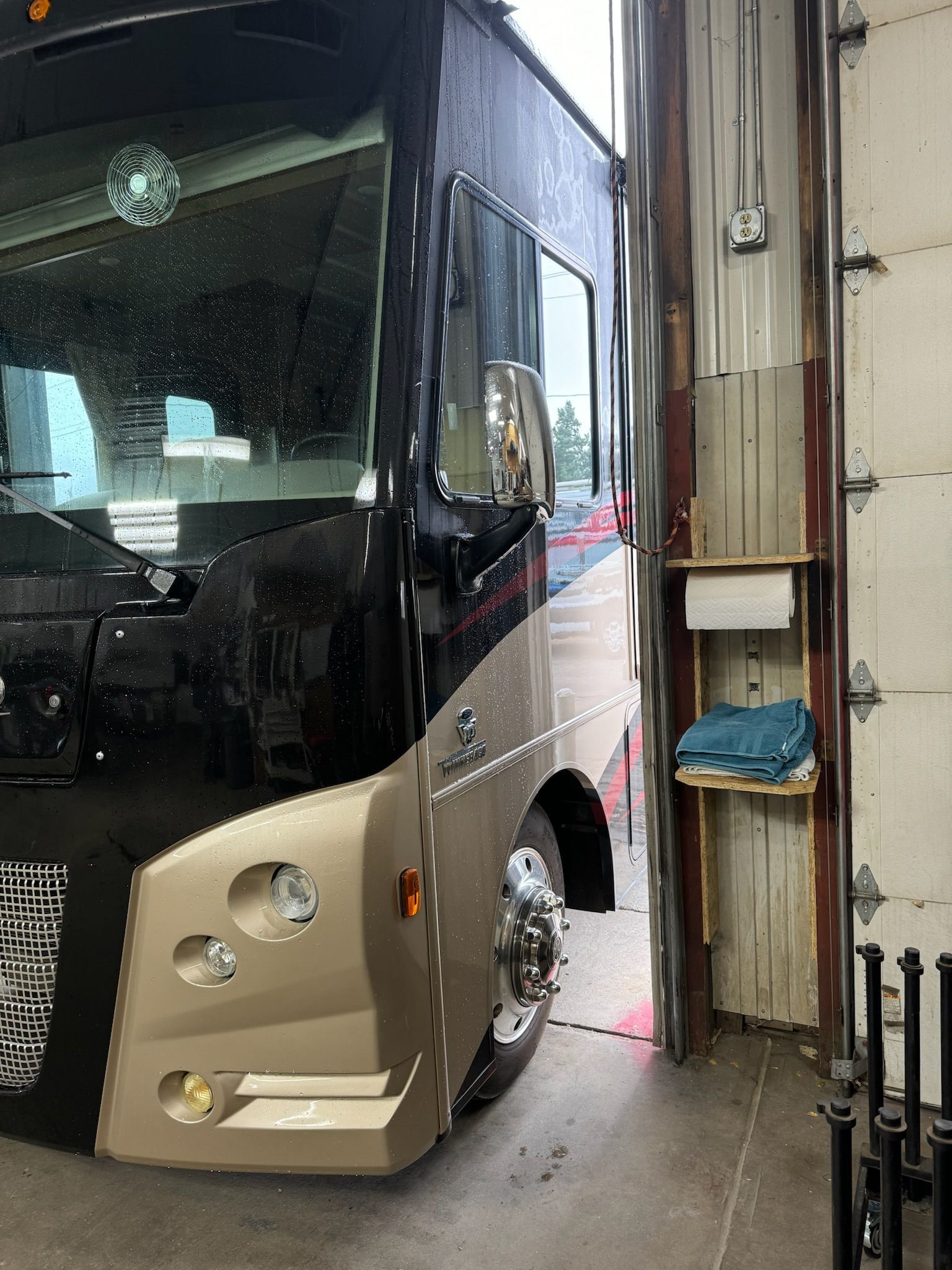 A large bus is parked in a garage next to a garage door.