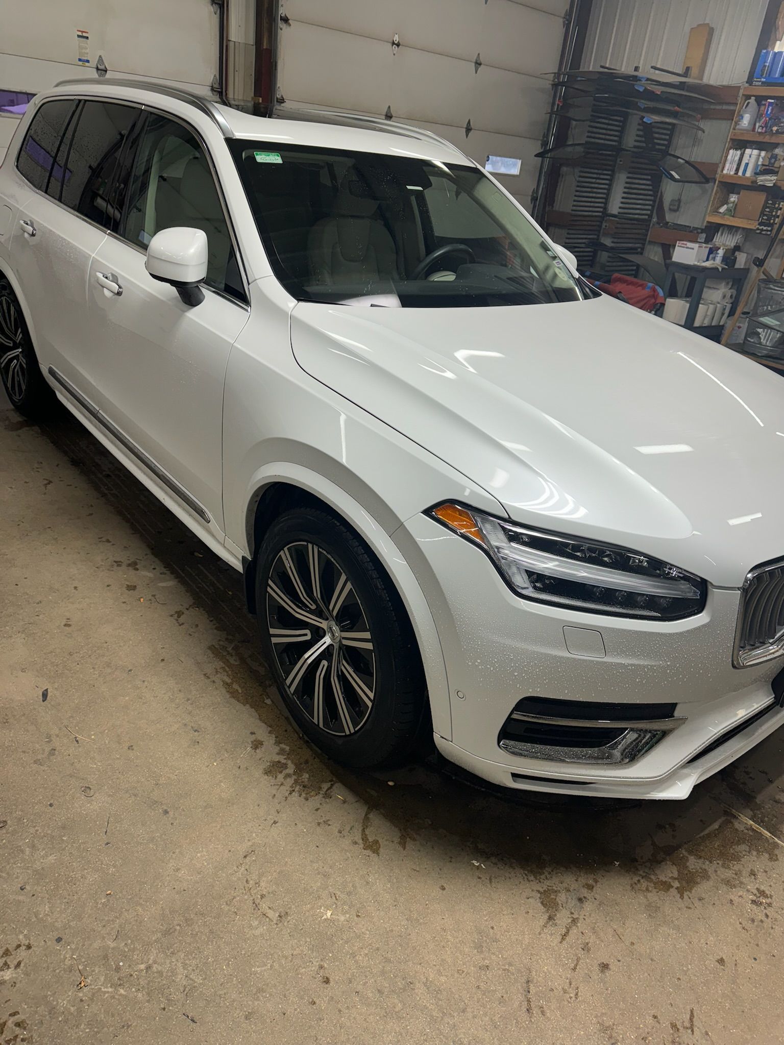A white volvo xc90 is parked in a garage.