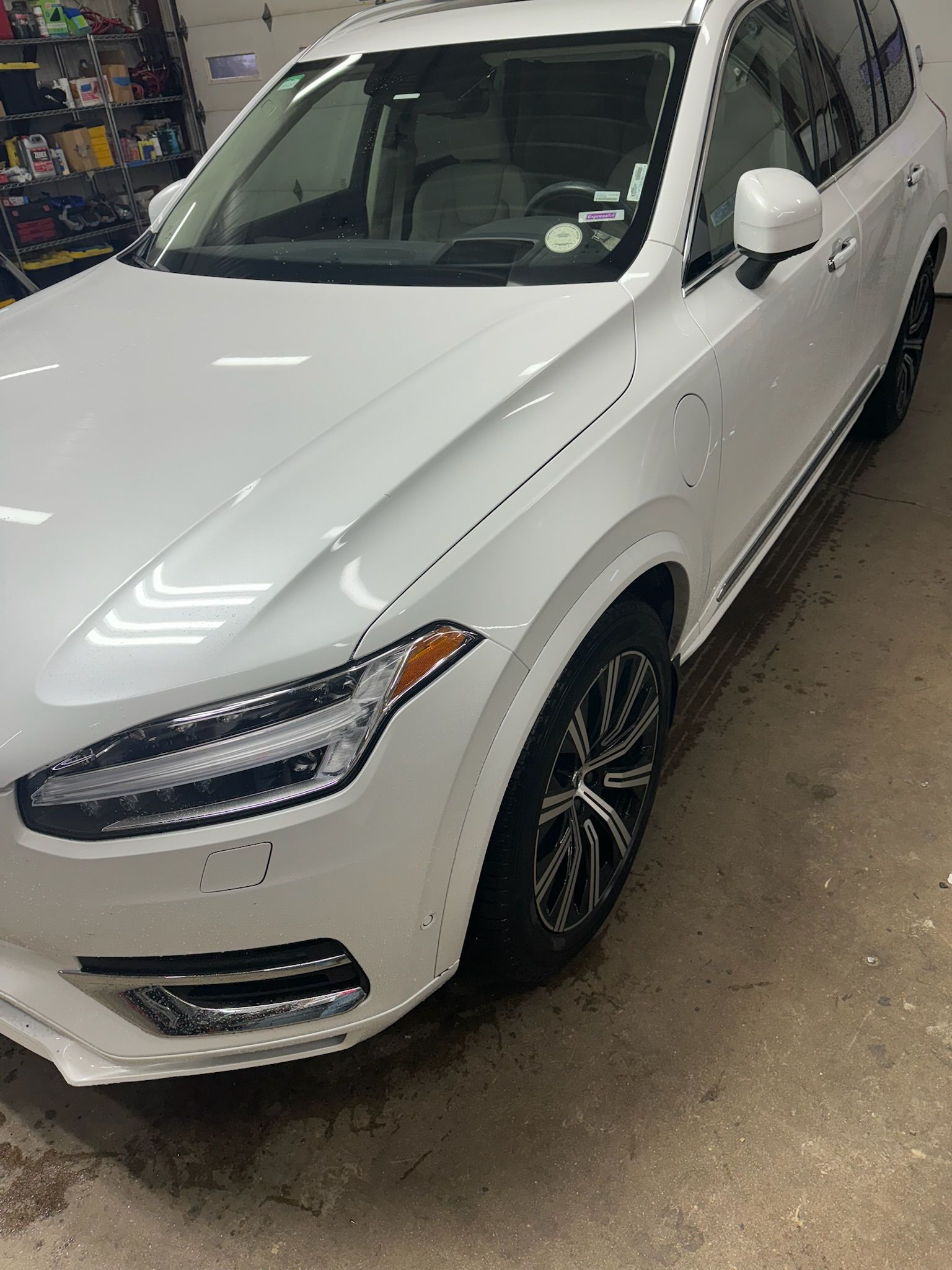 A white volvo xc90 is parked in a garage.