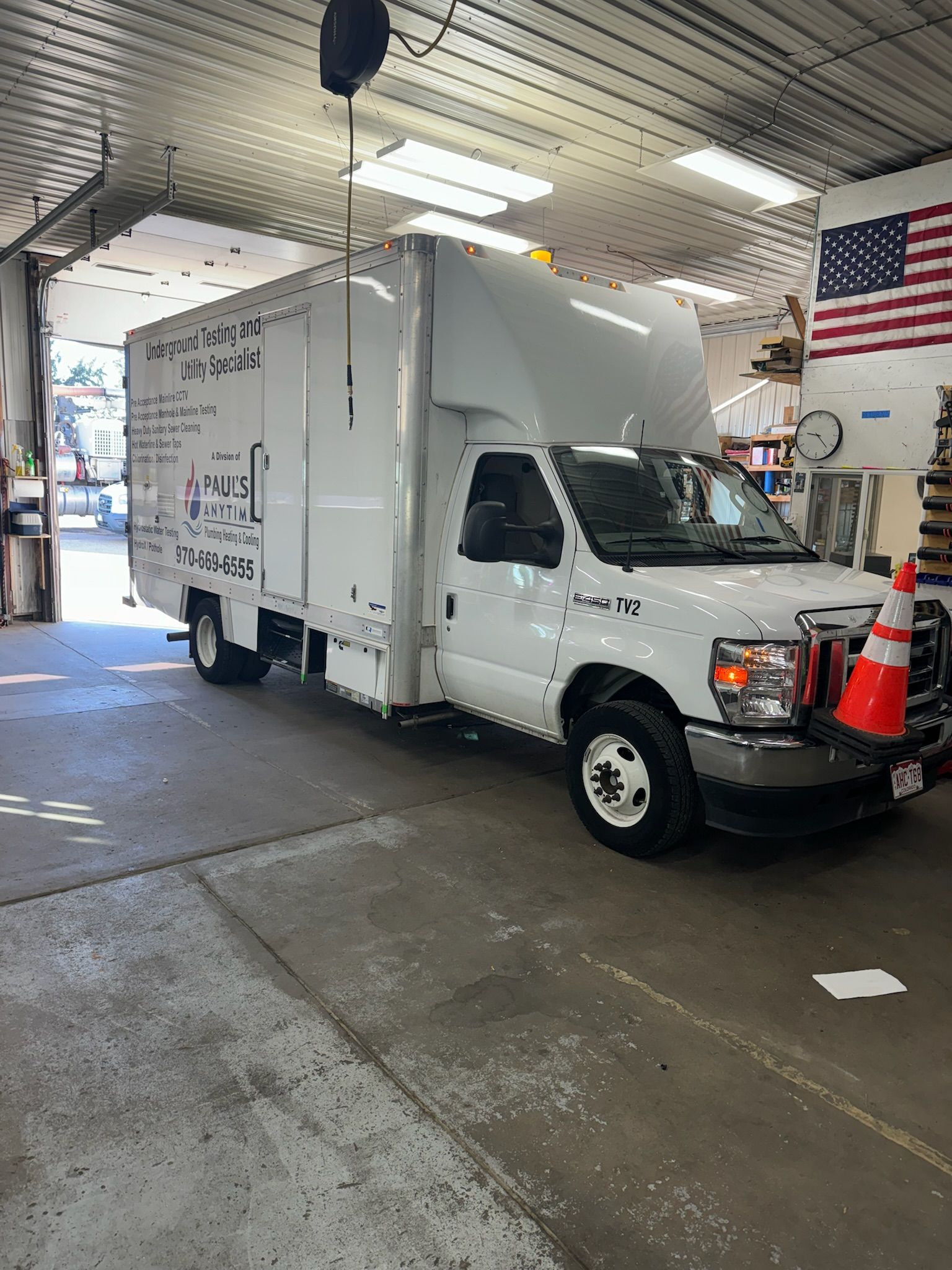 A white truck is parked in a garage next to a cone.