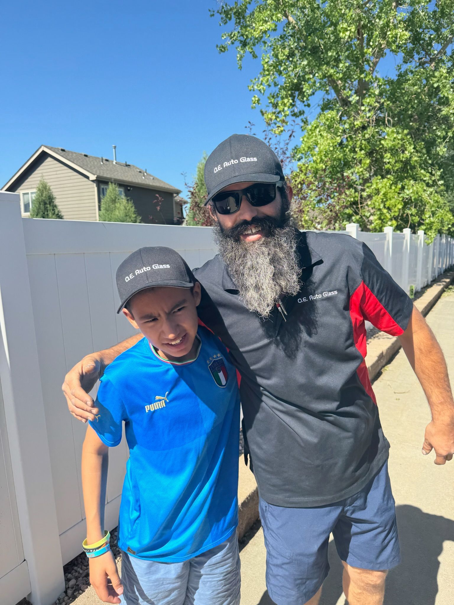A man with a beard and sunglasses is standing next to a boy.
