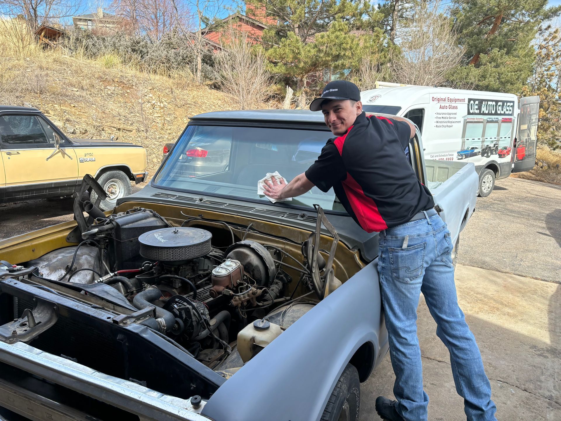 A man is cleaning the windshield of a truck.