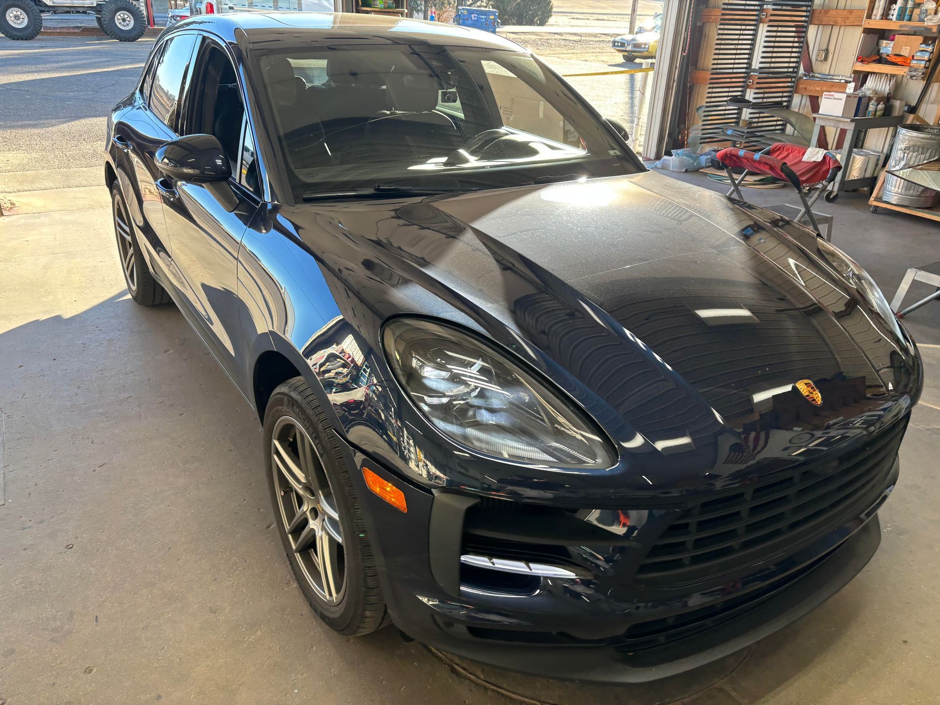 A black porsche macan is parked in a garage.
