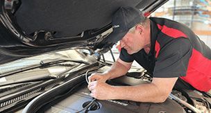 A man is working under the hood of a car.