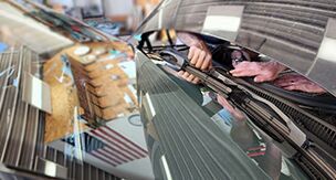 A person is cleaning the windshield of a car.