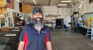 A man with a beard and mustache is standing in a garage.
