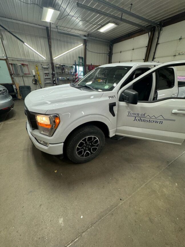 A white truck is parked in a garage with the door open.