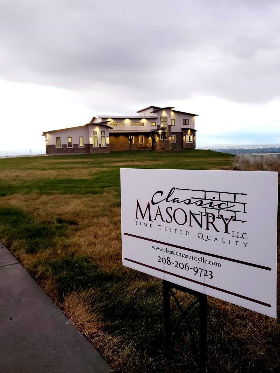 A sign for classic masonry llc is in front of a large house
