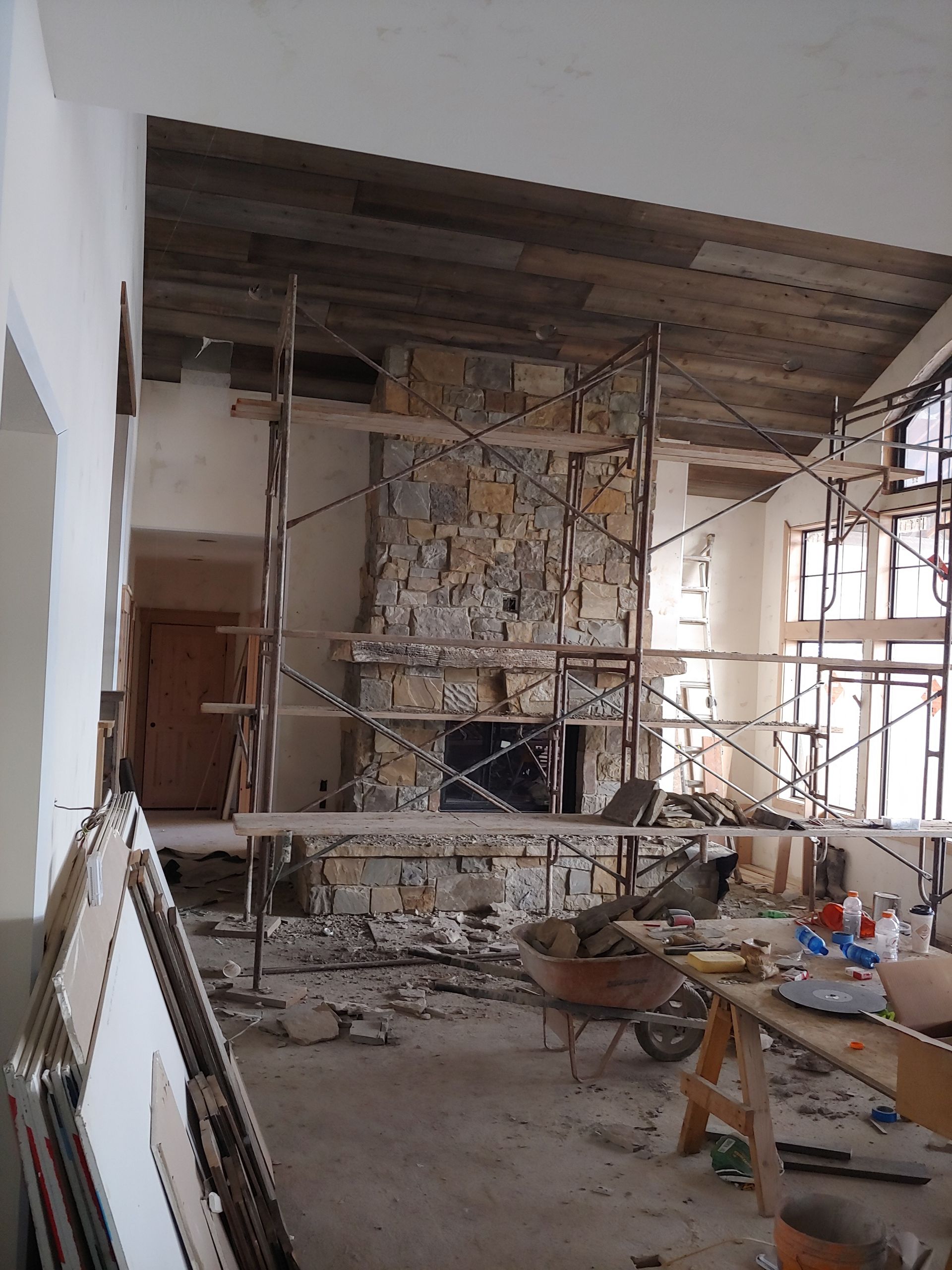 A room under construction with scaffolding and a stone fireplace