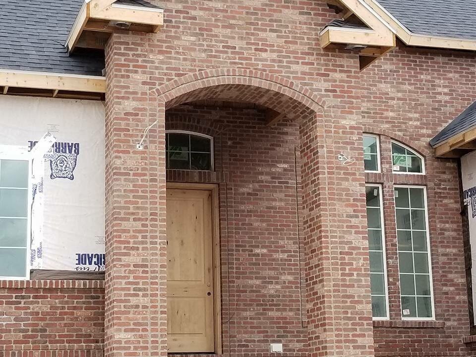 A brick house with a wooden door and windows under construction