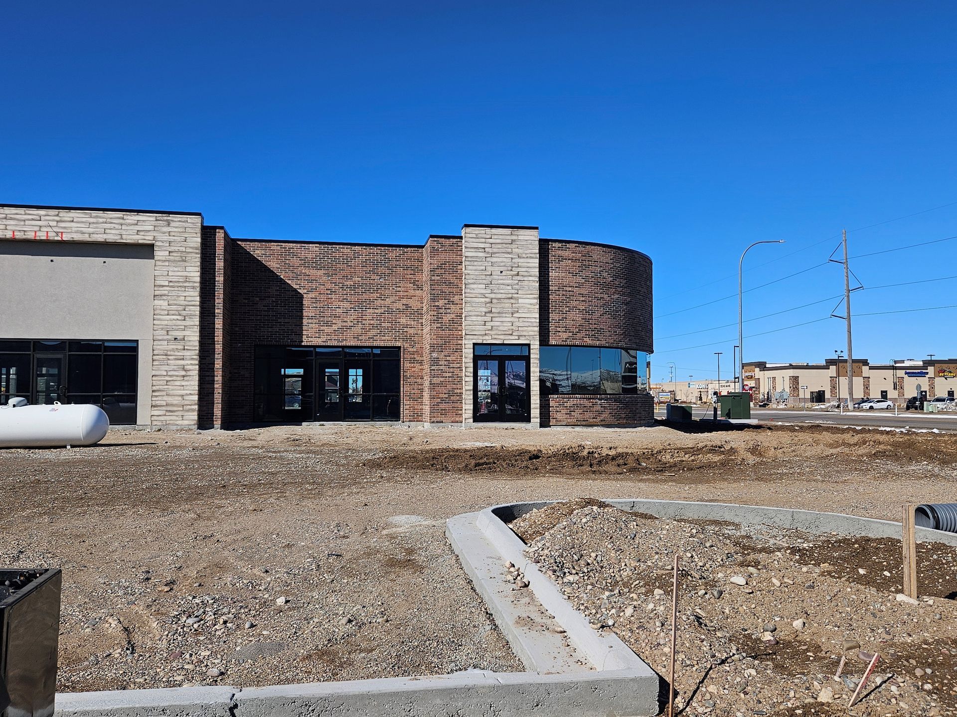 A brick building is being built in a dirt field