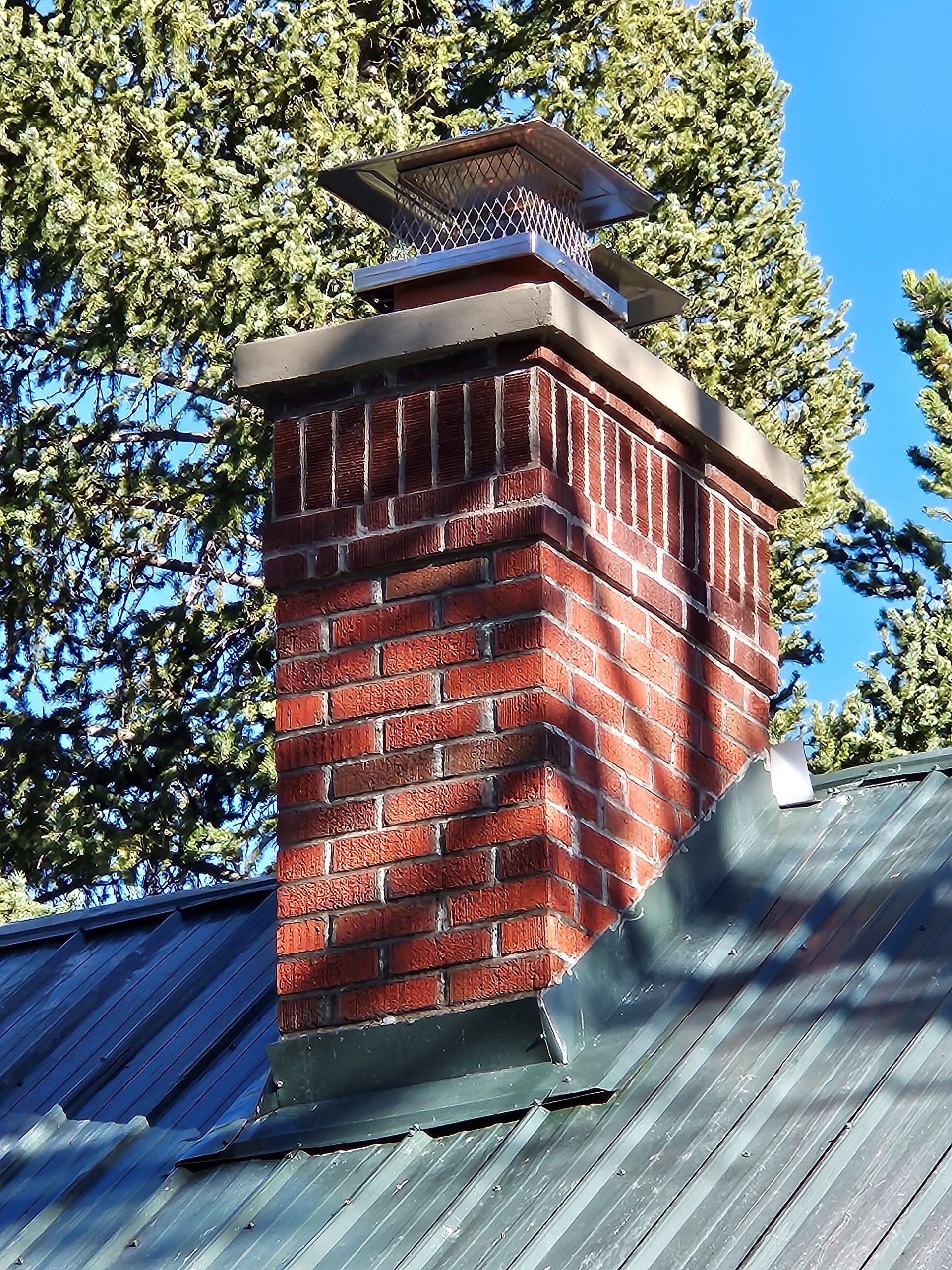 A brick chimney on top of a metal roof