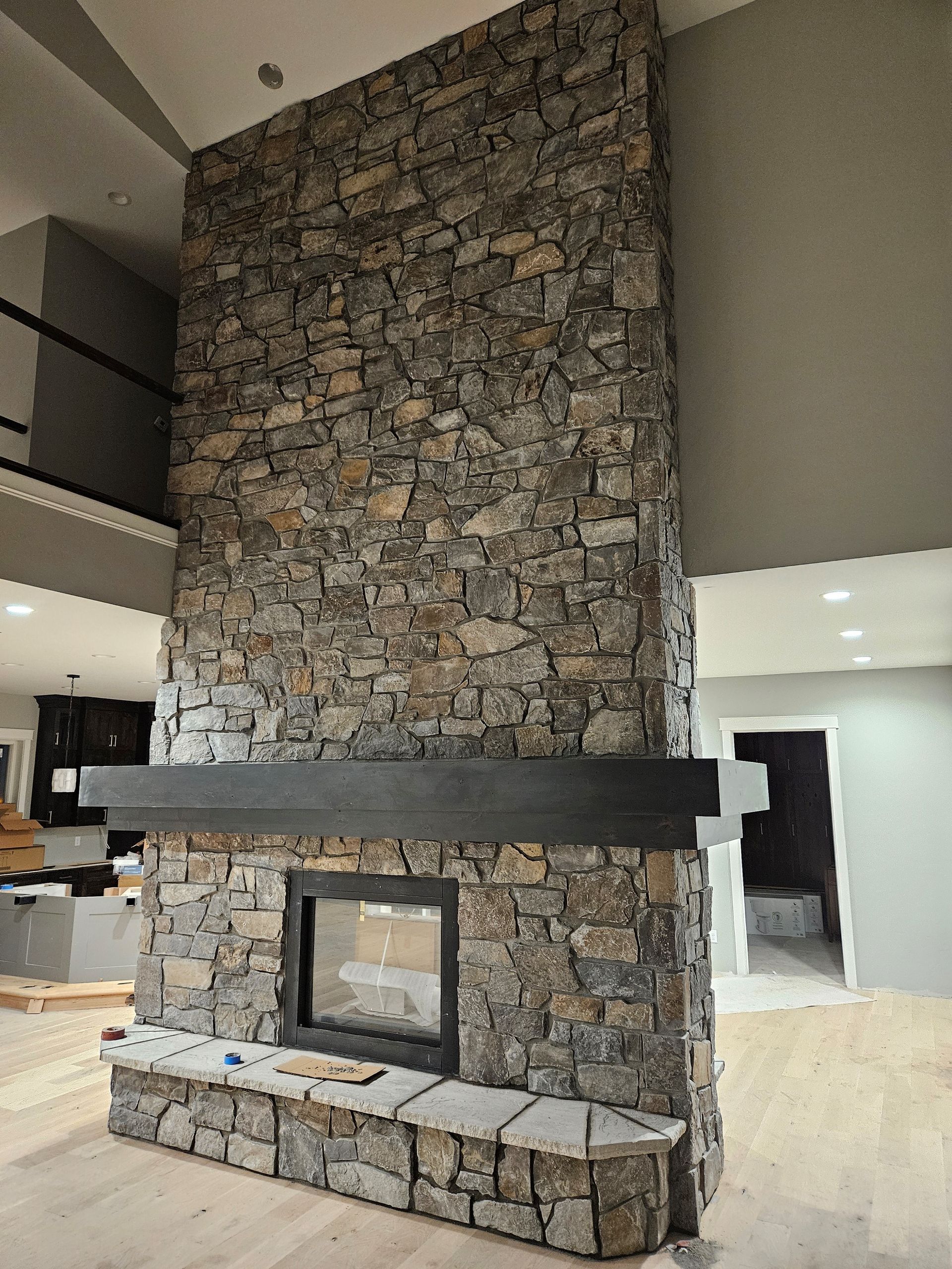 A large stone fireplace with a black mantle in a living room
