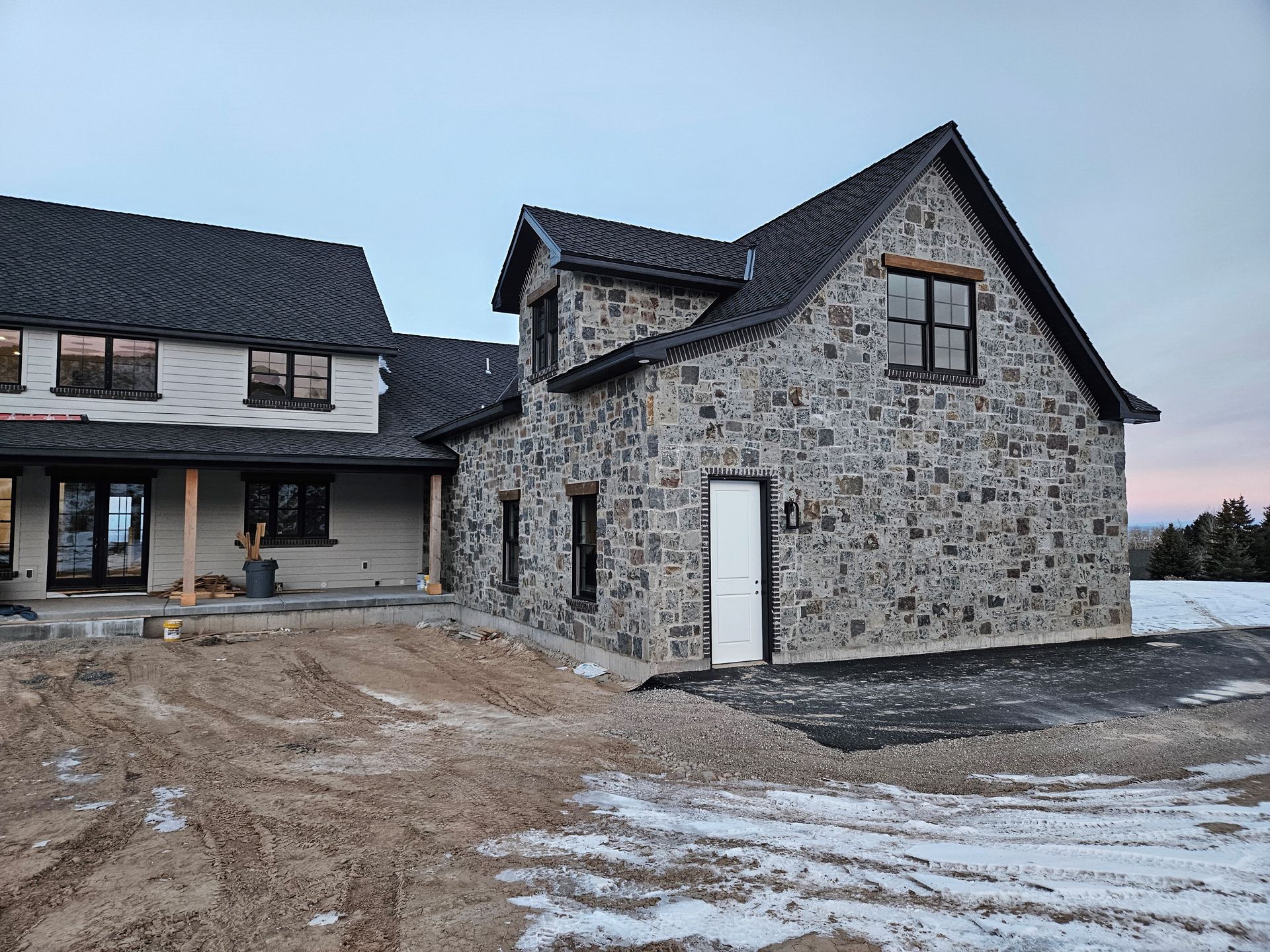 A large stone house is being built in a snowy field
