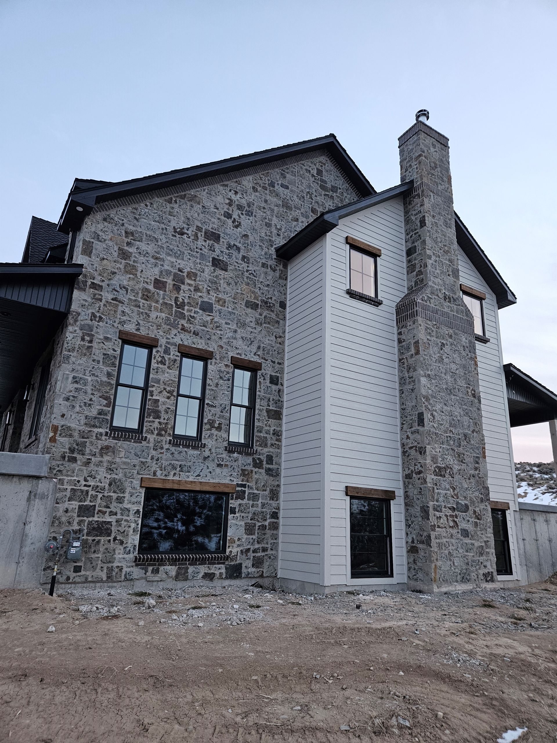 A large stone house with a chimney on top of it is being built