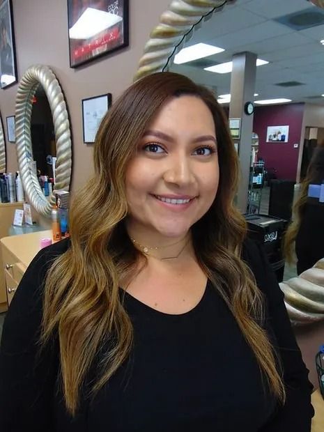 Woman with brown hair smiling in a salon, wearing a black top.