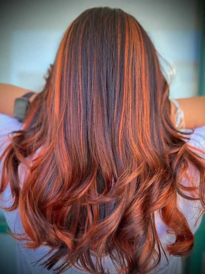 Long wavy hair with red and orange highlights against a light background.