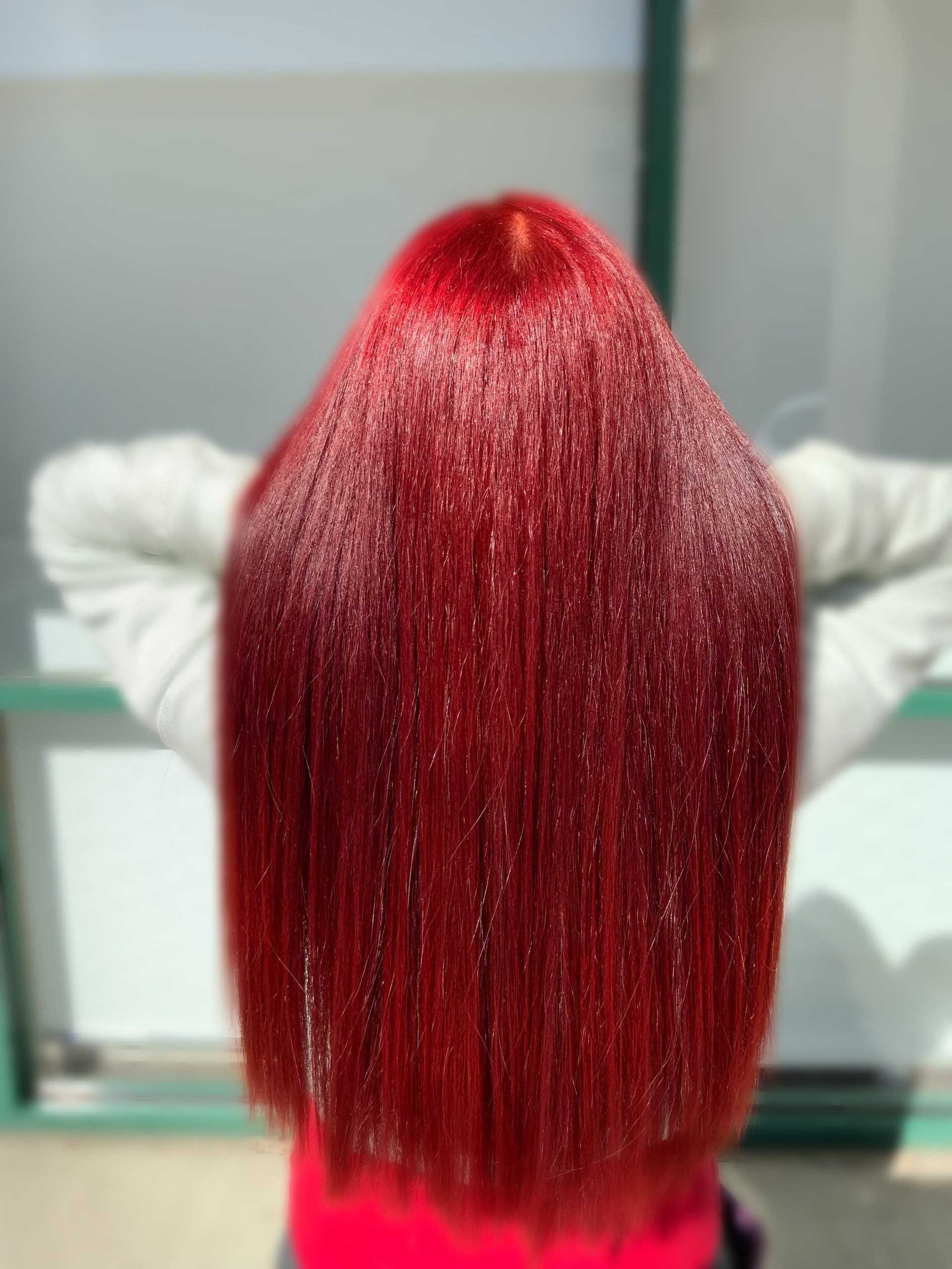 Long, vibrant red hair, possibly glittered, against a blurred background.