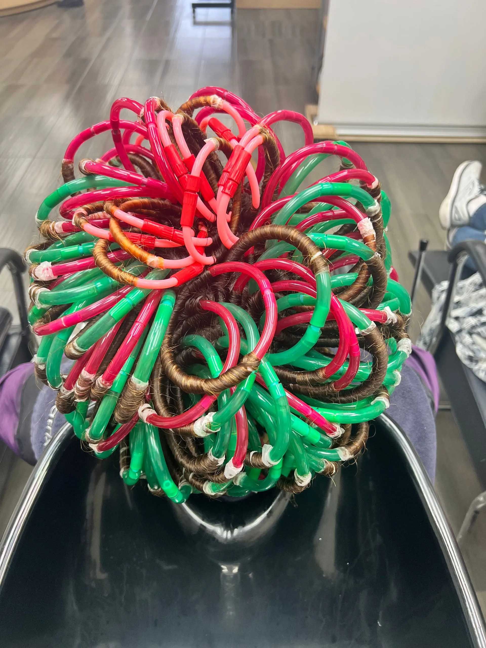 Close-up of vibrant hair styled with green, red, and brown looped strands.