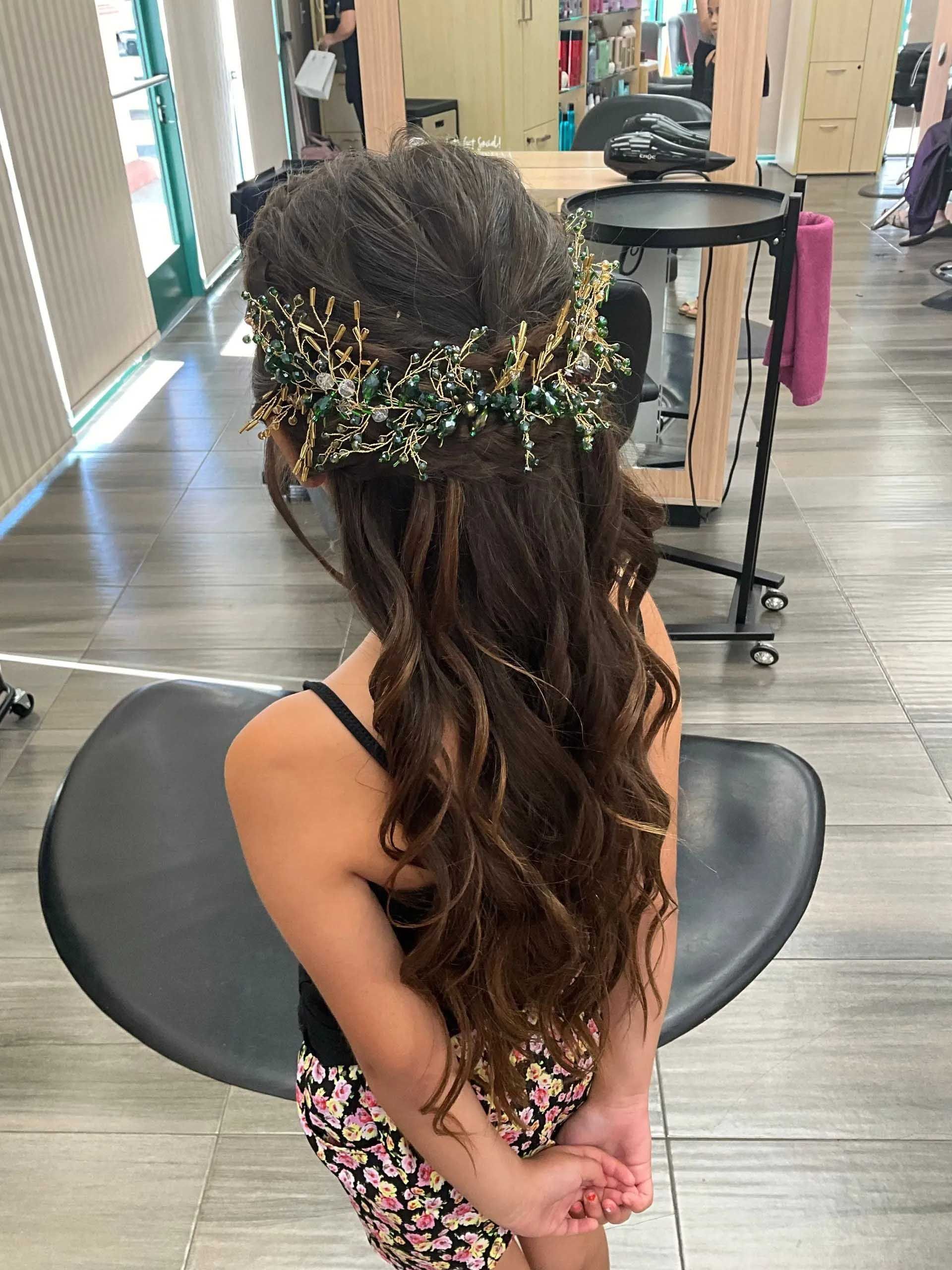 Girl with long wavy brown hair, wearing a floral crown, in a salon.