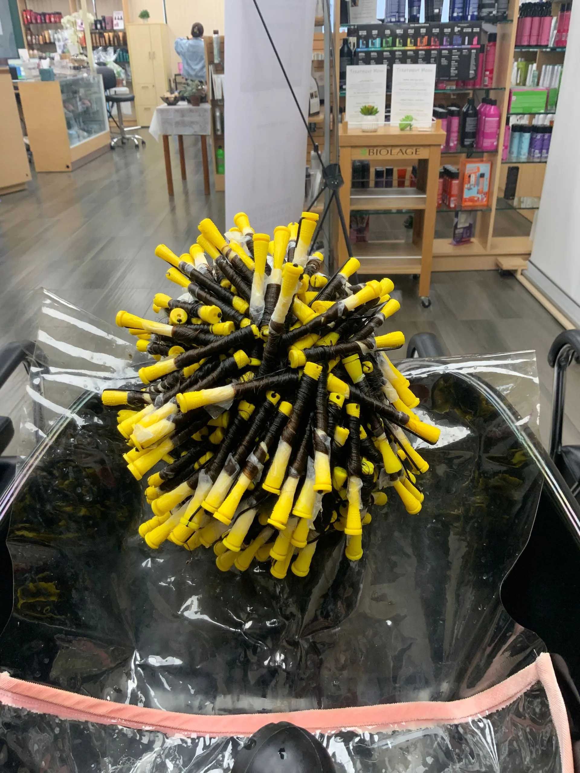 A bundle of yellow and black perm rods on a chair in a salon.