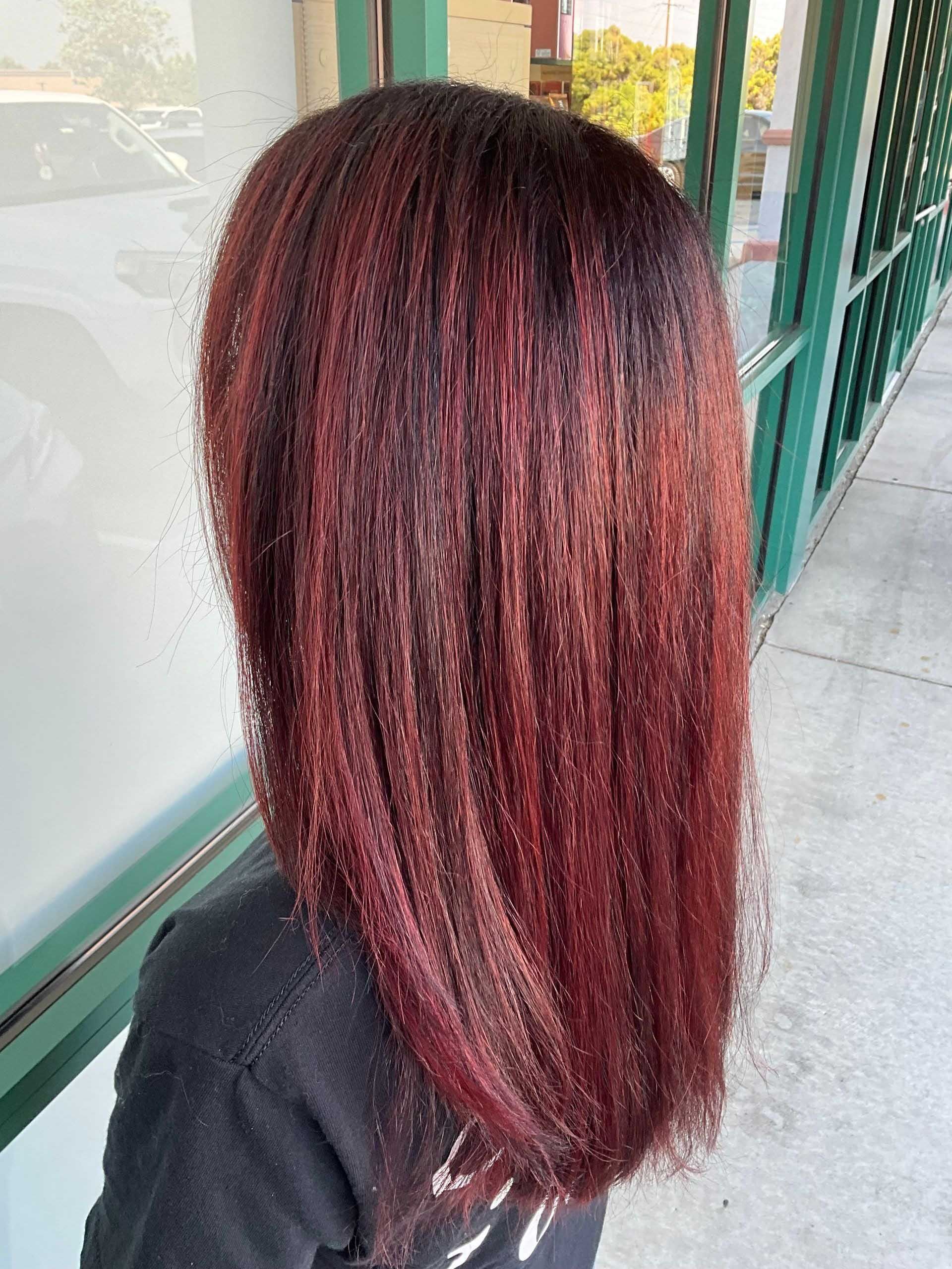 Shoulder-length, straight red hair with dark roots. Person wearing a black shirt. Outdoors, near a window.