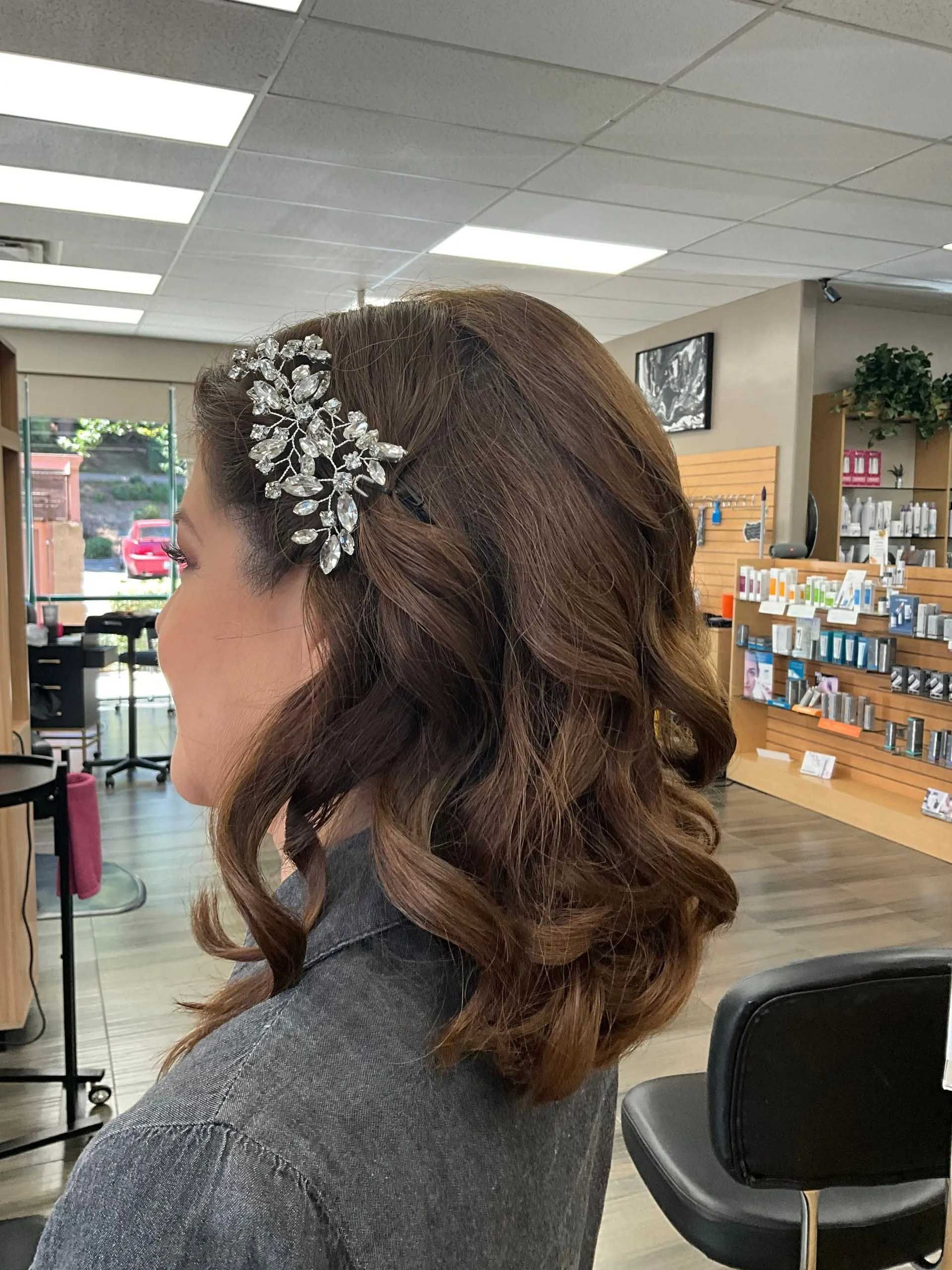 Woman with brown, curly hair, adorned with jeweled hair accessory, in a salon.