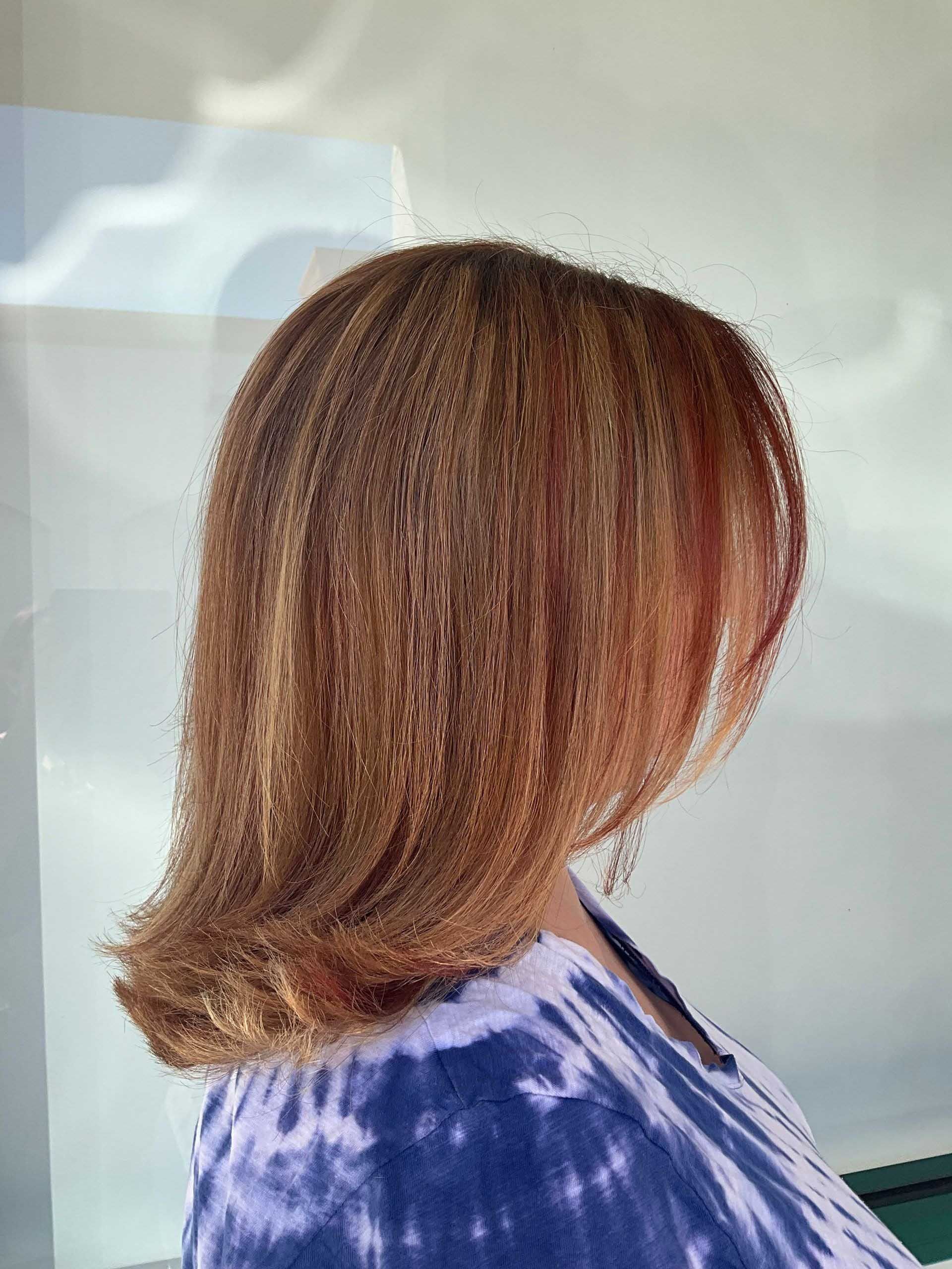 Woman with light brown, shoulder-length hair; wearing a blue tie-dye top, outdoors.