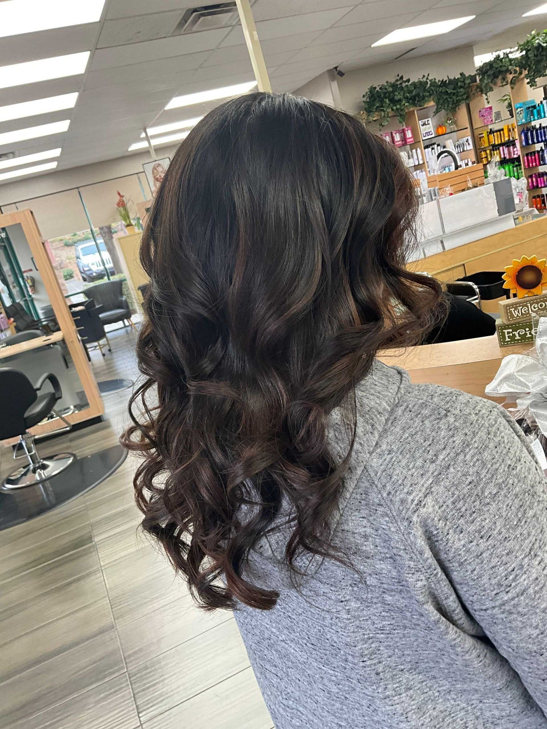 Woman with wavy dark brown hair styled at a salon.