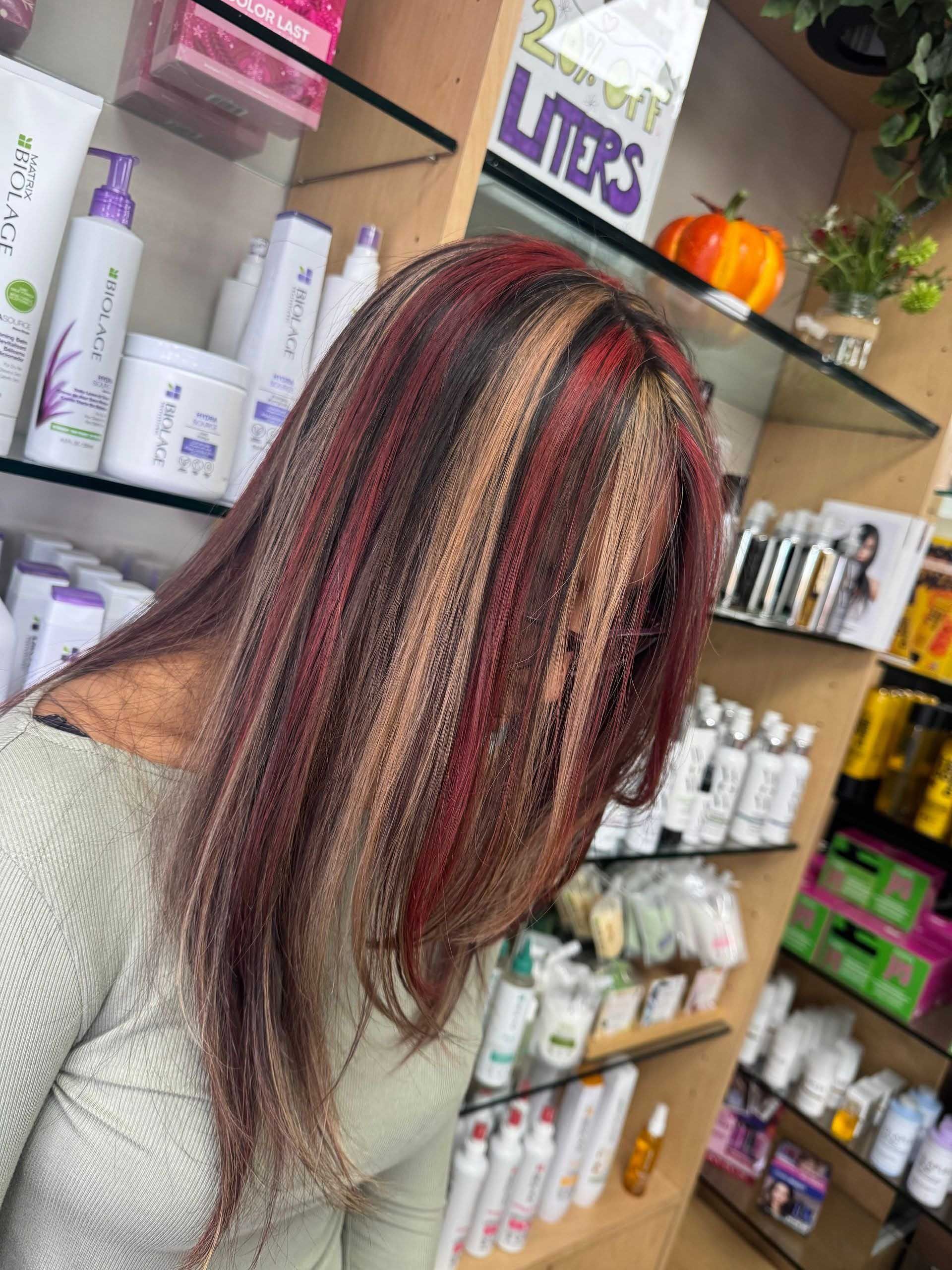 Person with long hair, highlighted red, brown, and blonde, in a beauty supply store.