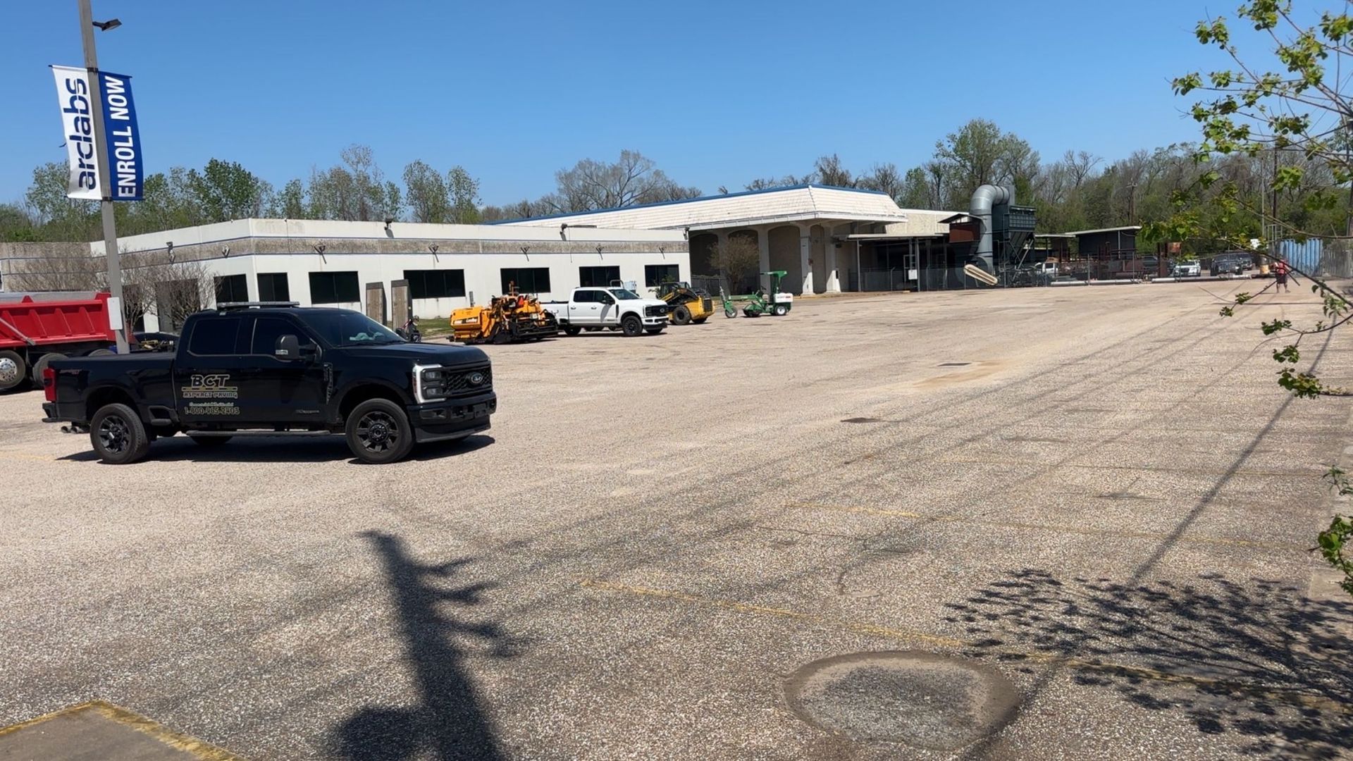 A gravel lot with construction vehicles and a building with 
