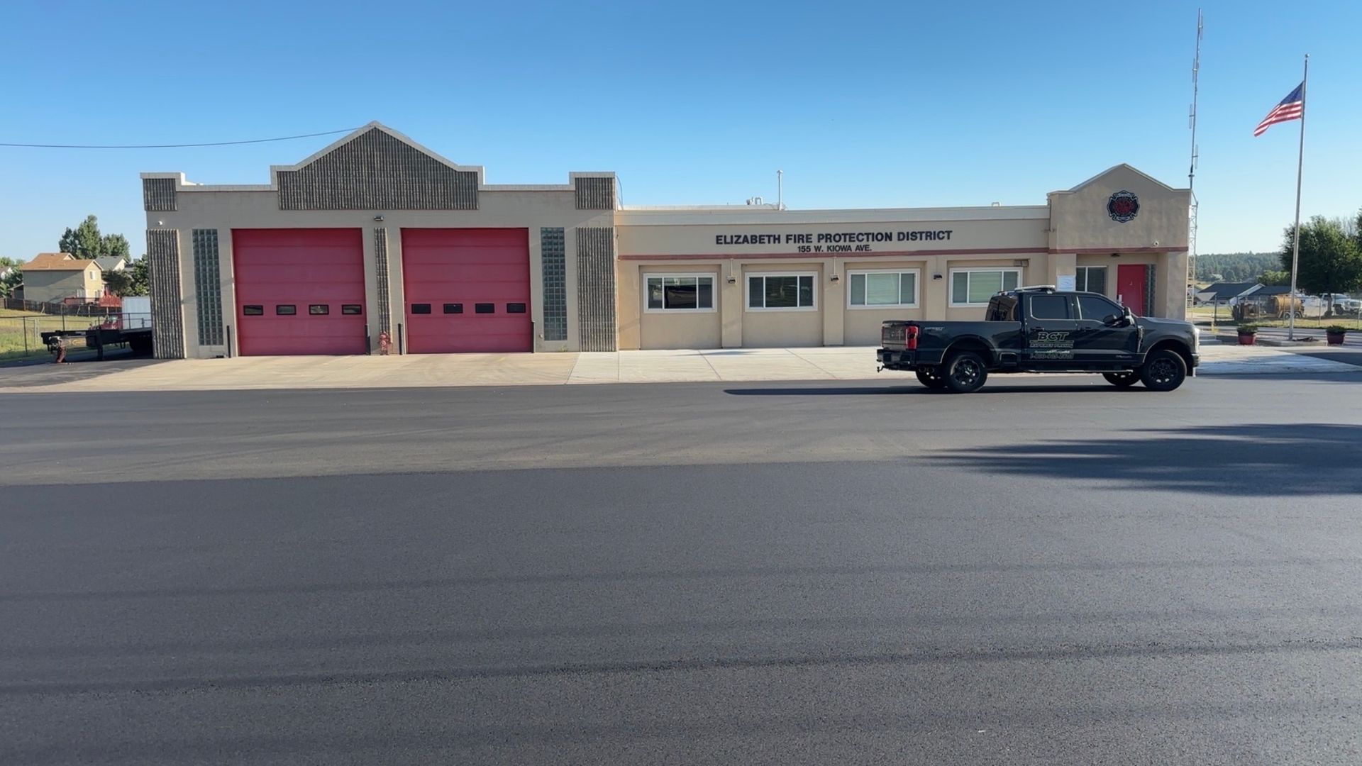 Fire station with red garage doors, a pickup truck parked out front.