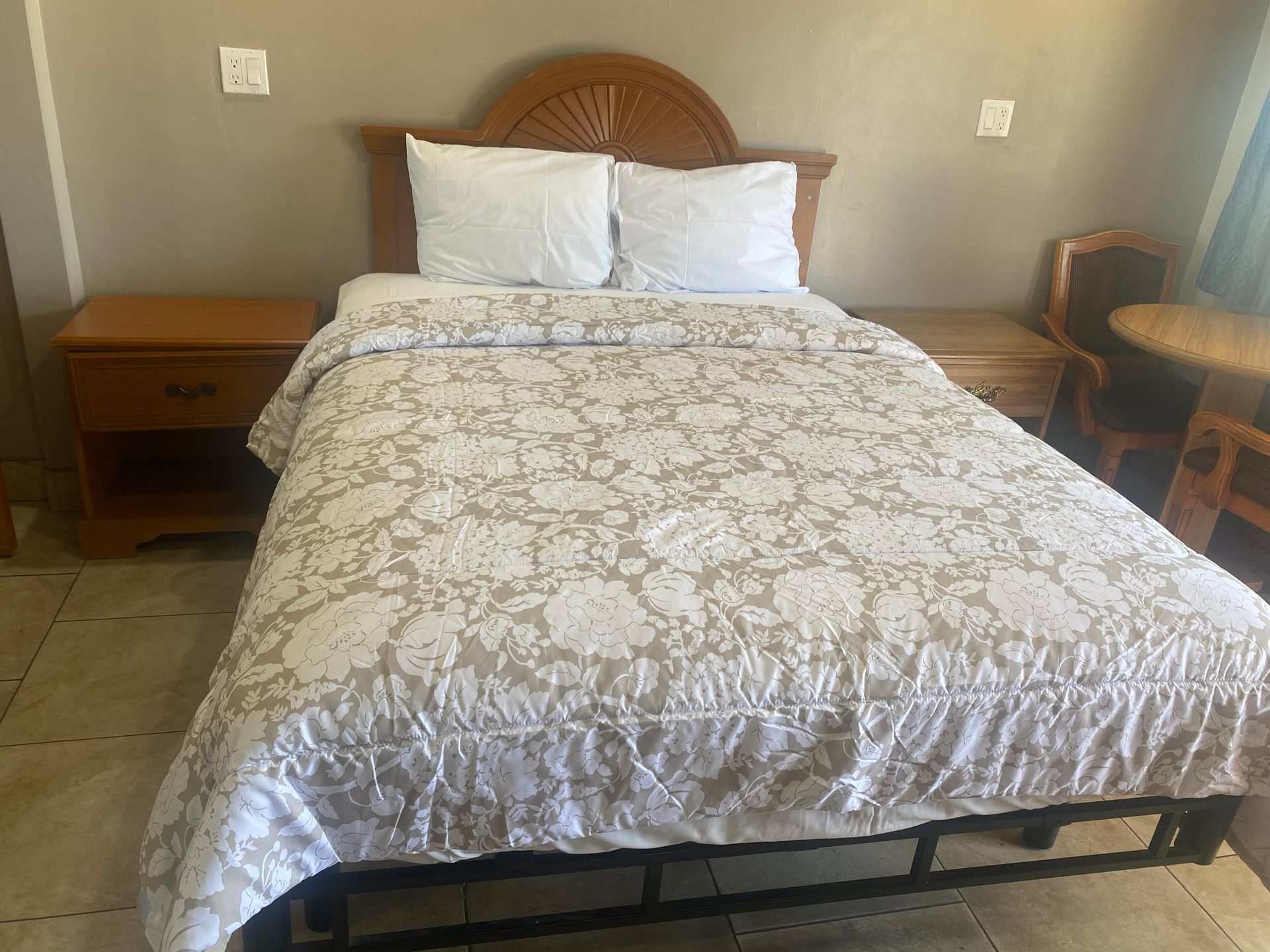 A hotel room with a bed , nightstand , chair and table.