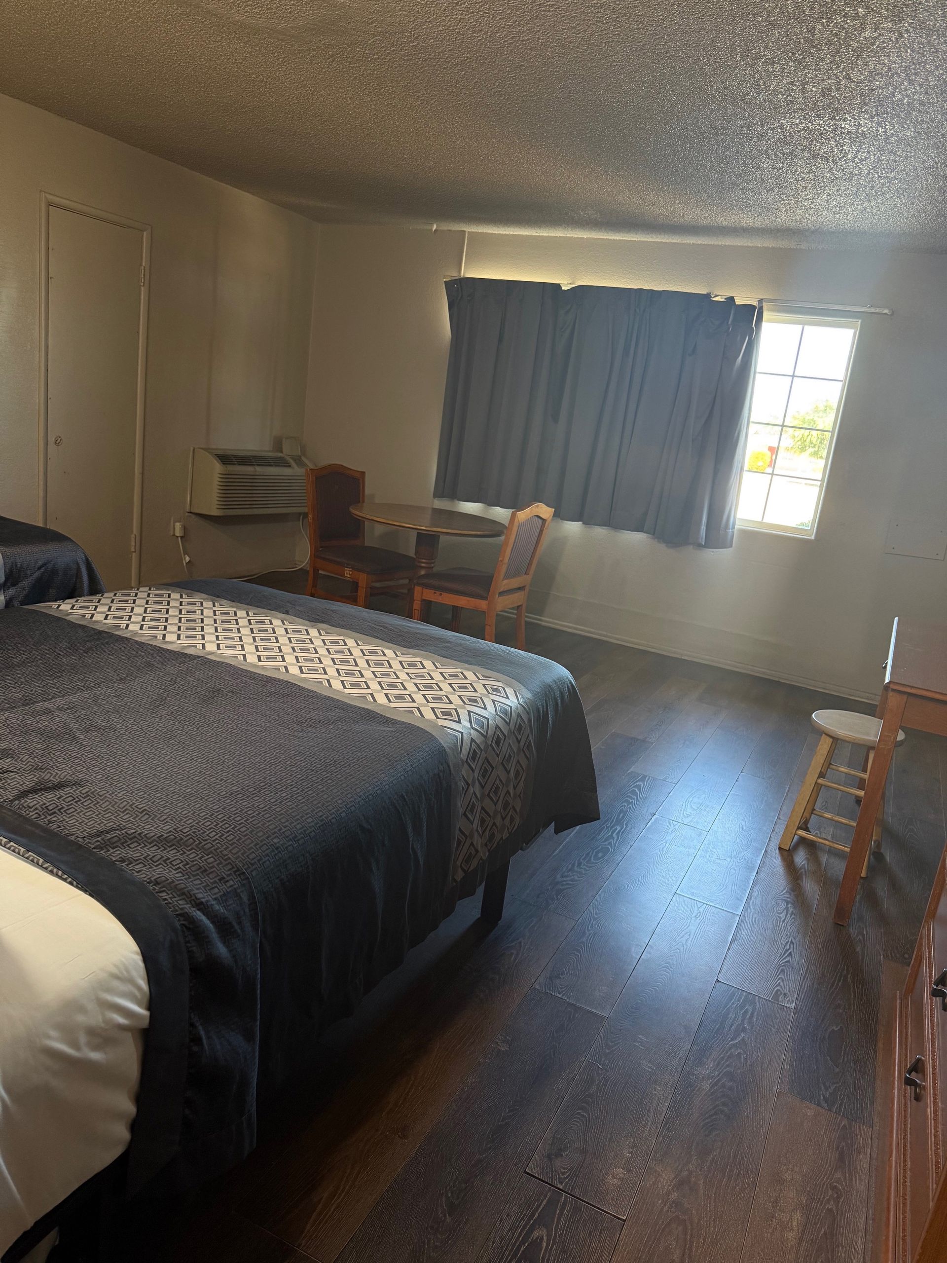 A hotel room with two beds , a chair , a desk and a window.