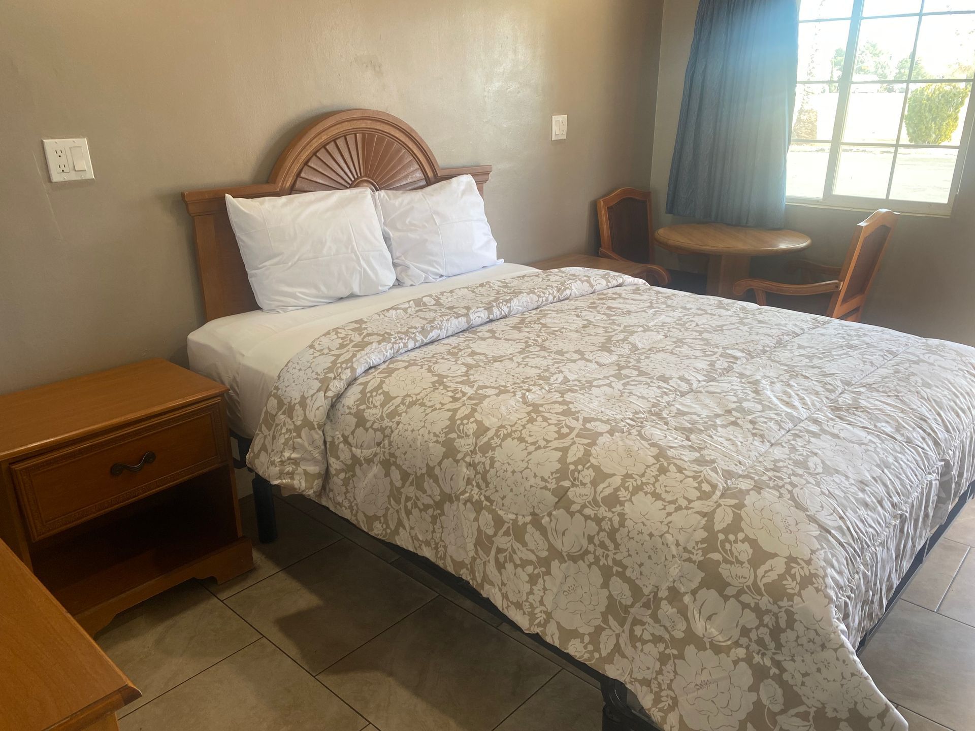 A hotel room with a bed , nightstand , table and chairs.