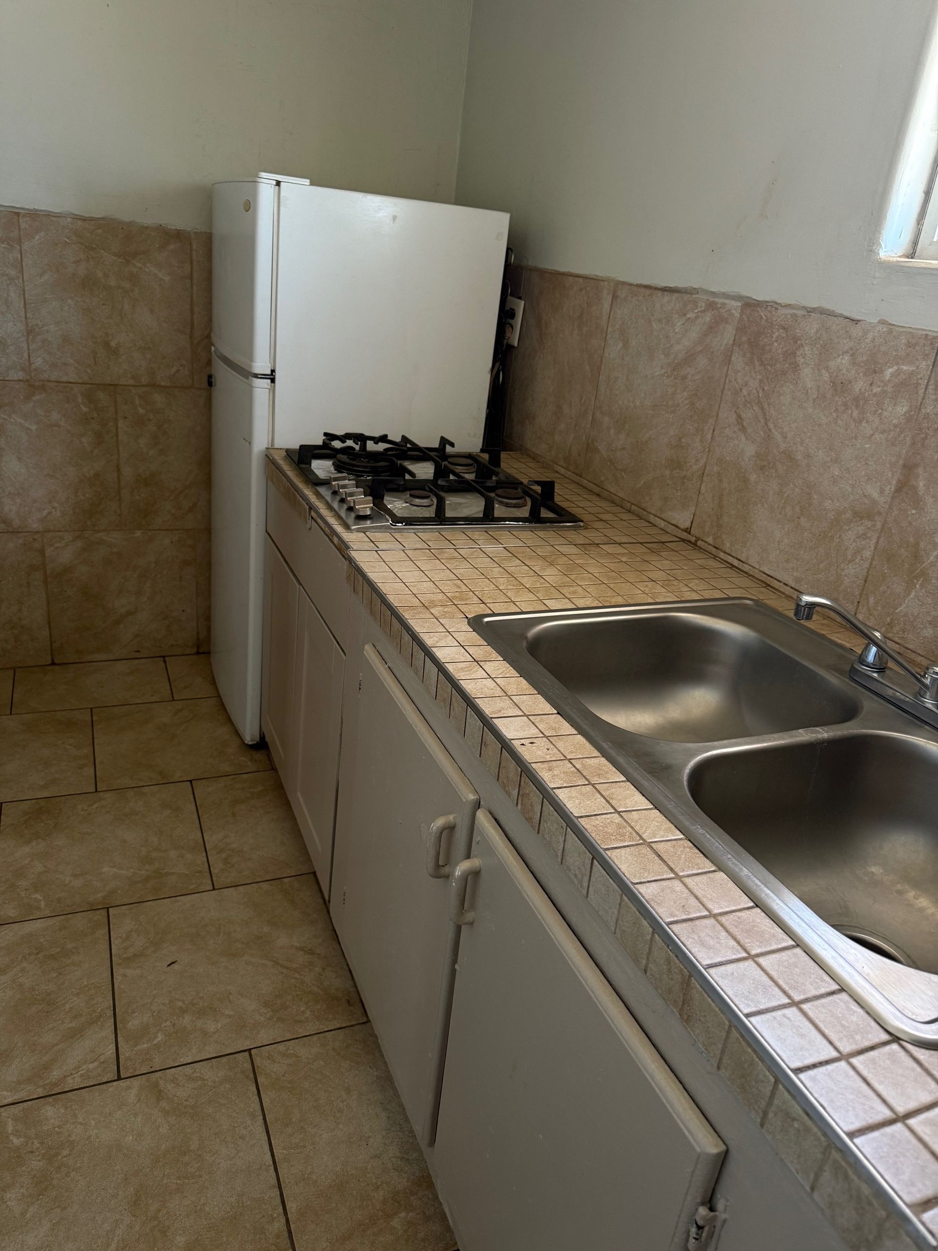 A kitchen with a sink stove and refrigerator