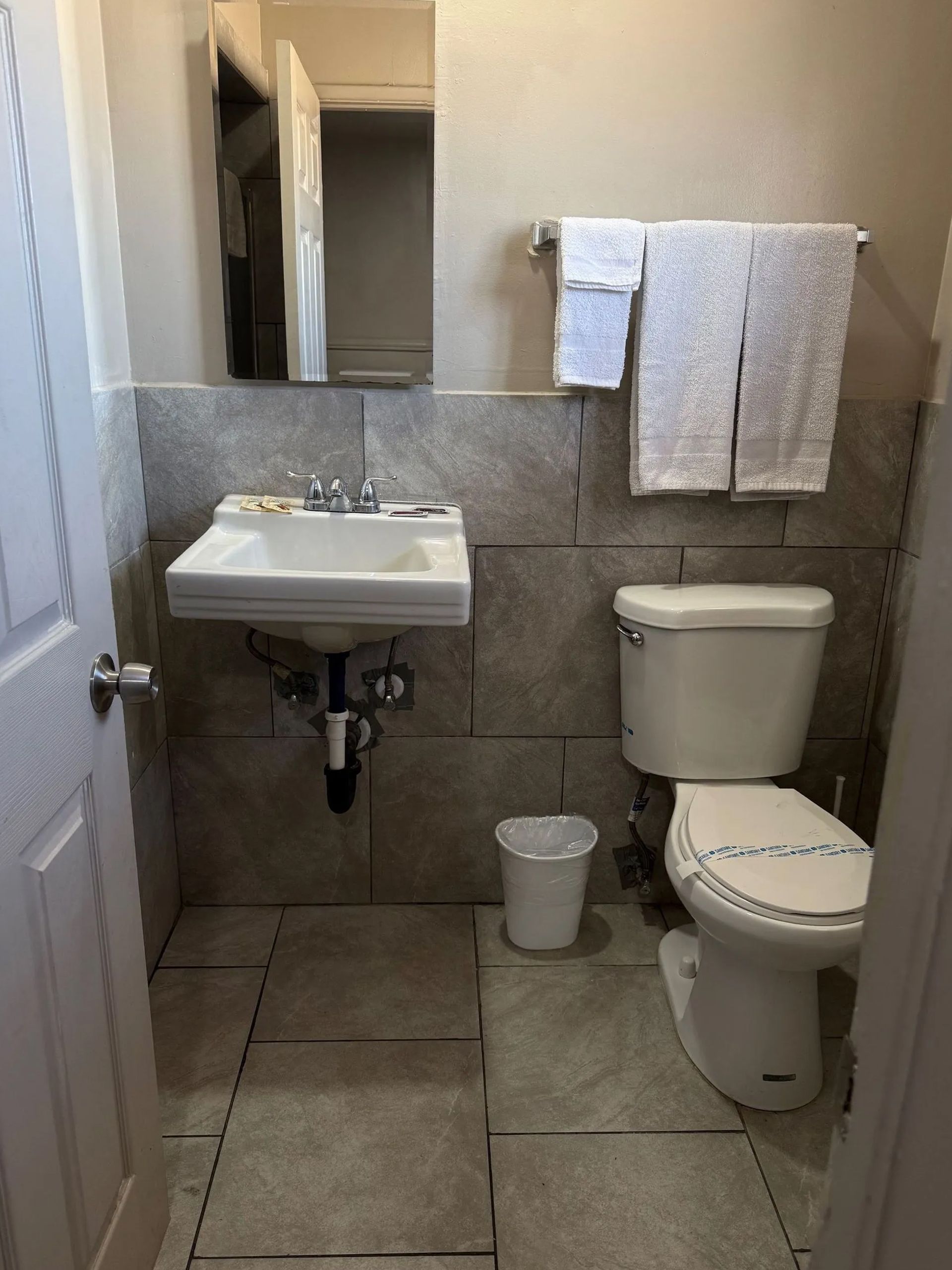 A bathroom with a sink , toilet and mirror.