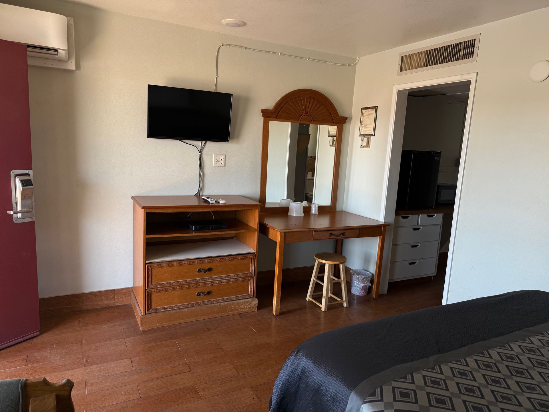 A hotel room with a bed , desk , television and mirror.