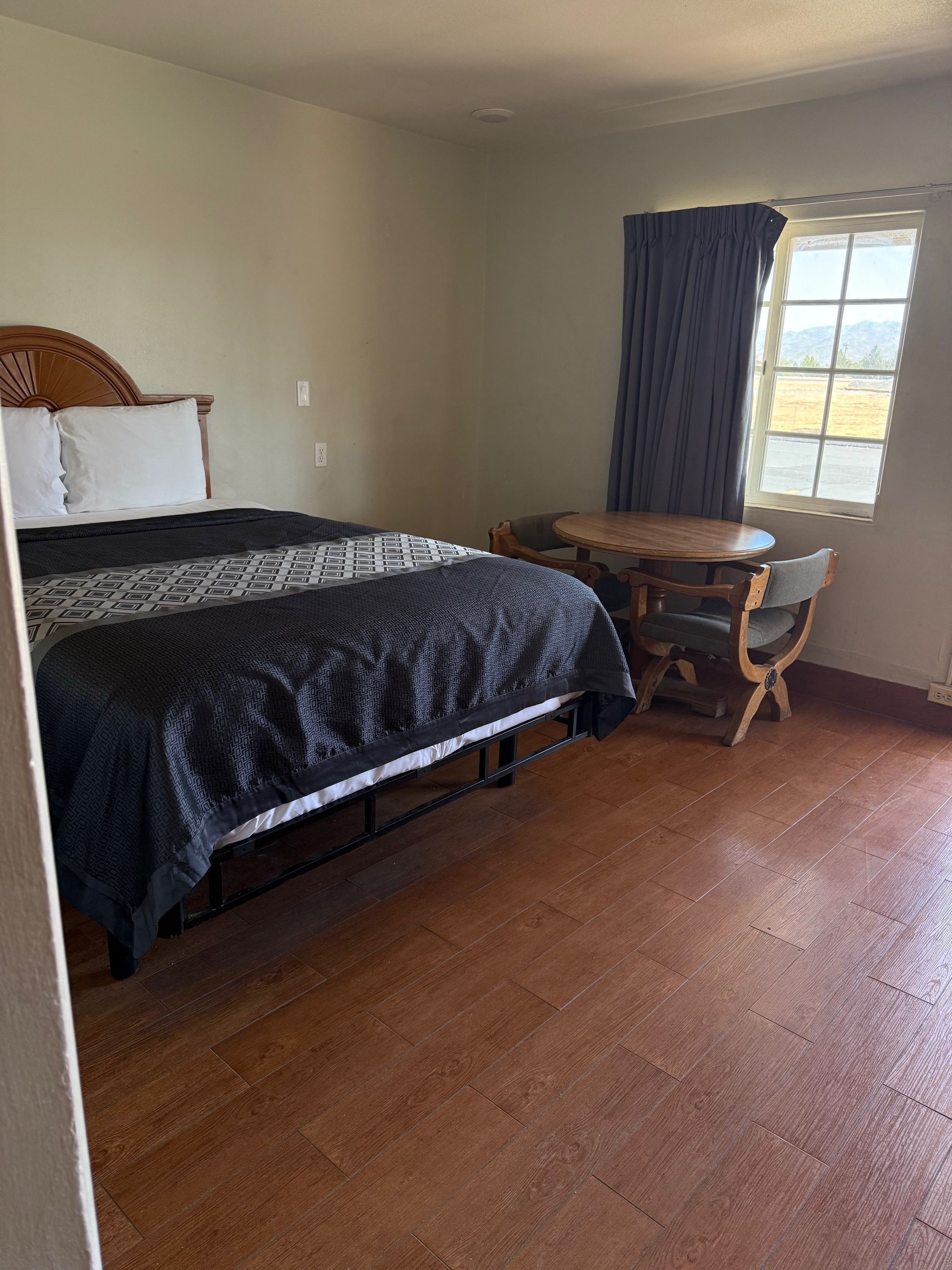 A hotel room with a bed , table and chairs.